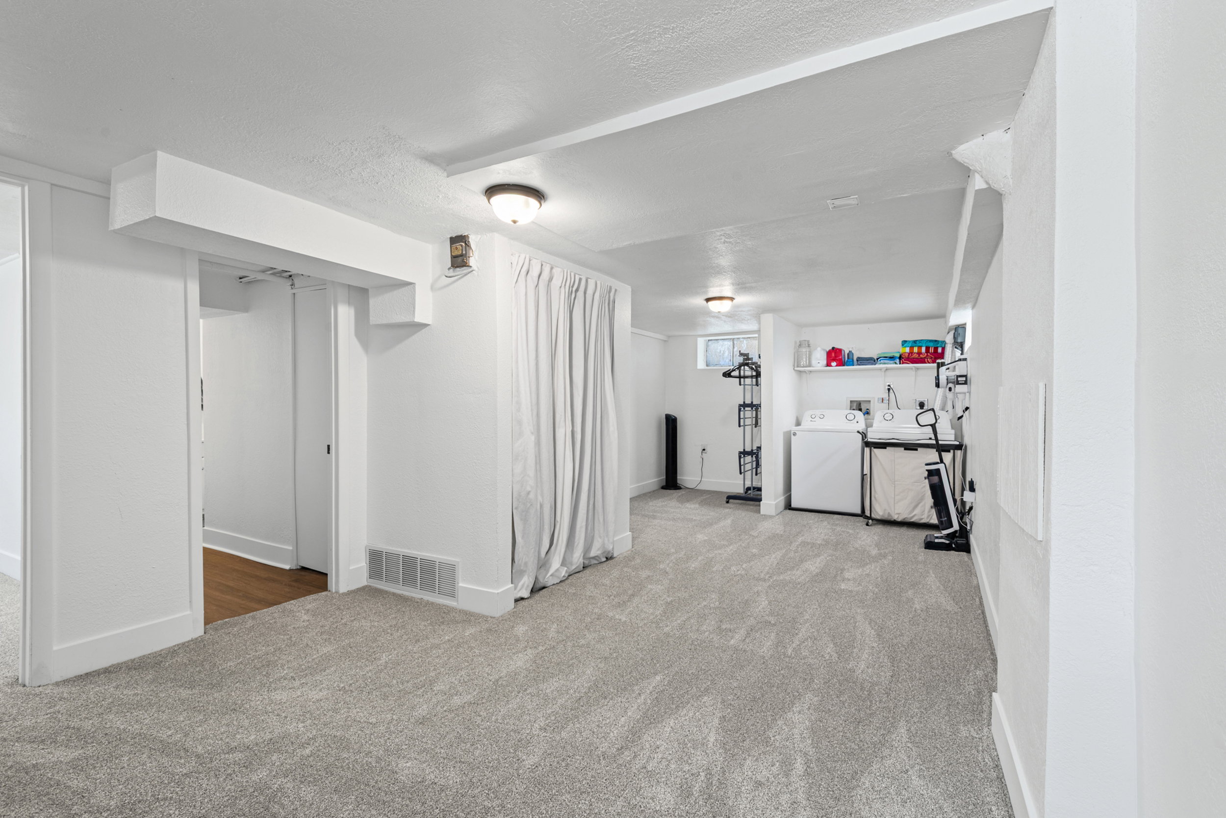 Spacious carpeted room featuring a dedicated laundry area with a utility sink, washer, and dryer