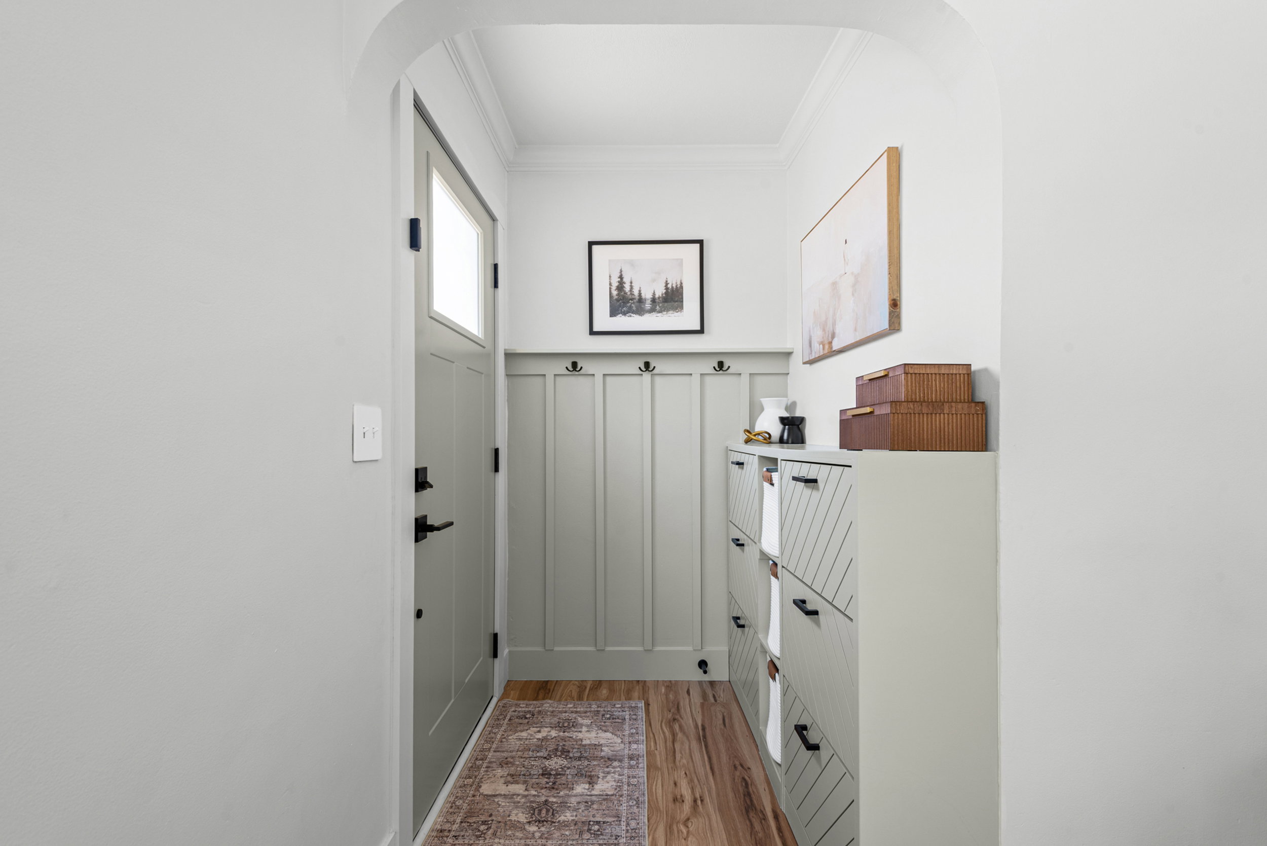 Entryway featuring wood-finish flooring, a light gray door with window pane, and board and batten paneling