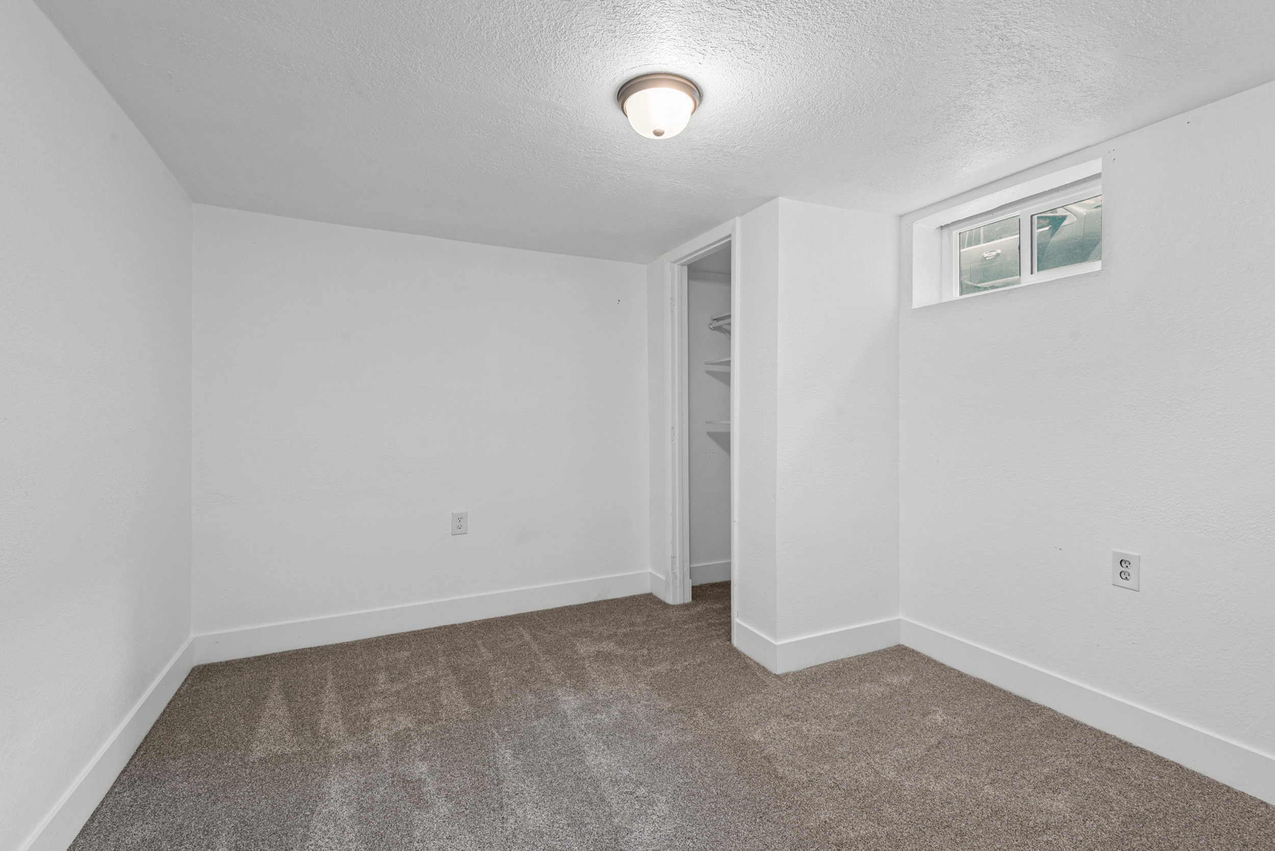Compact room featuring gray carpeting, white walls, and a single window