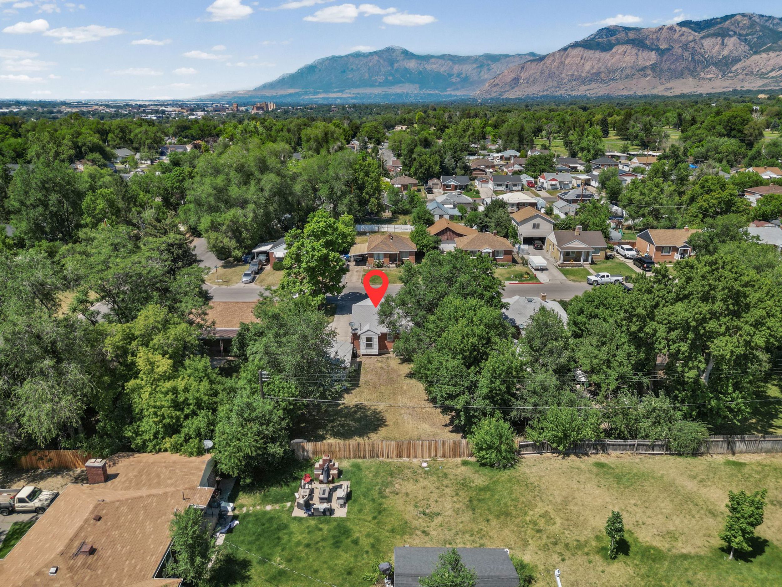 Aerial perspective of a property featuring a single-story residence with a light-colored exterior and dark roof