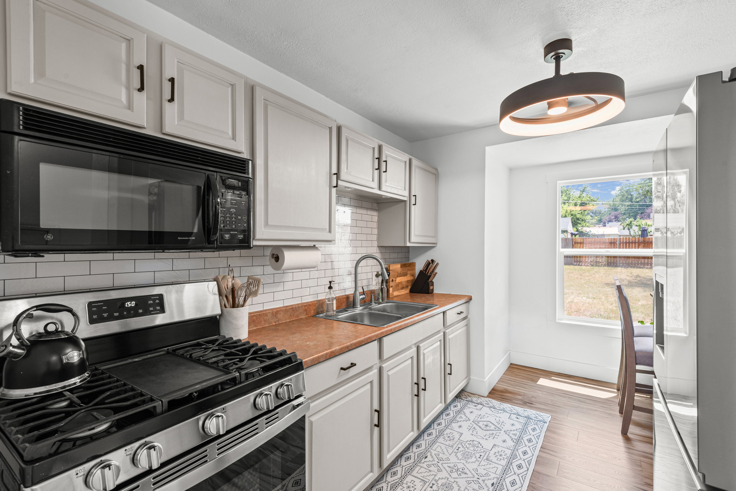 Kitchen featuring wood-finish flooring, white cabinetry with dark hardware, stainless steel range, and subway tile backsplash