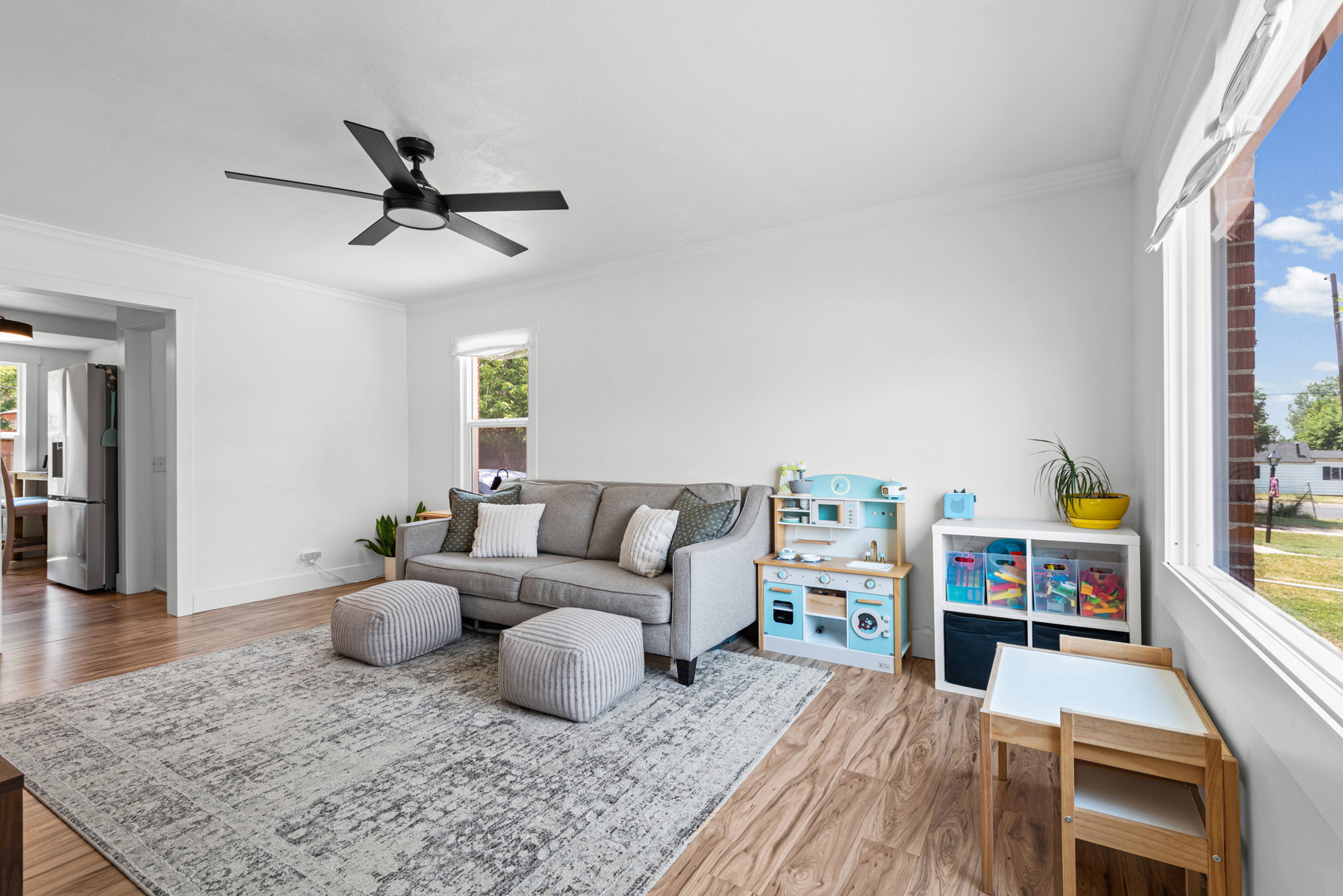 Living area featuring wood-finish flooring, white walls, crown molding, and a contemporary ceiling fan