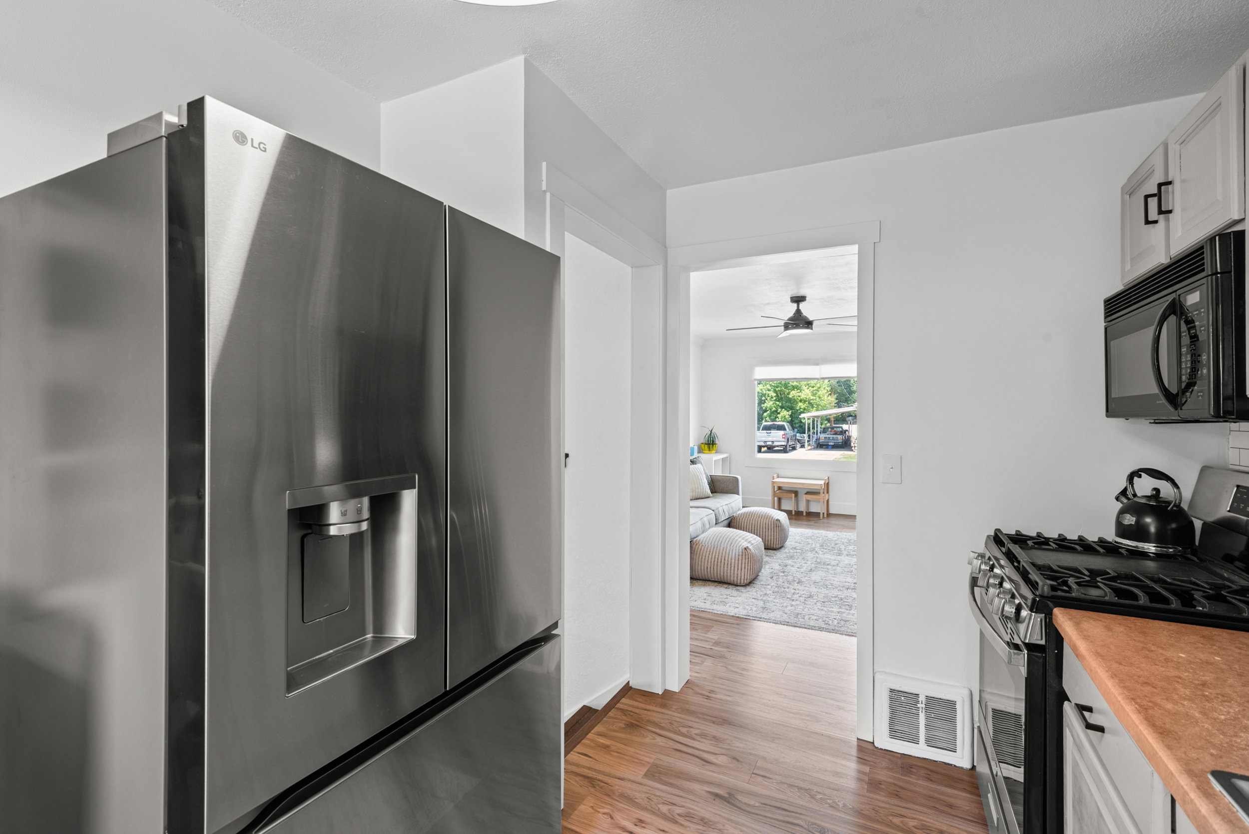 Kitchen featuring stainless steel appliances, wood-finish flooring, white cabinetry, and a gas range