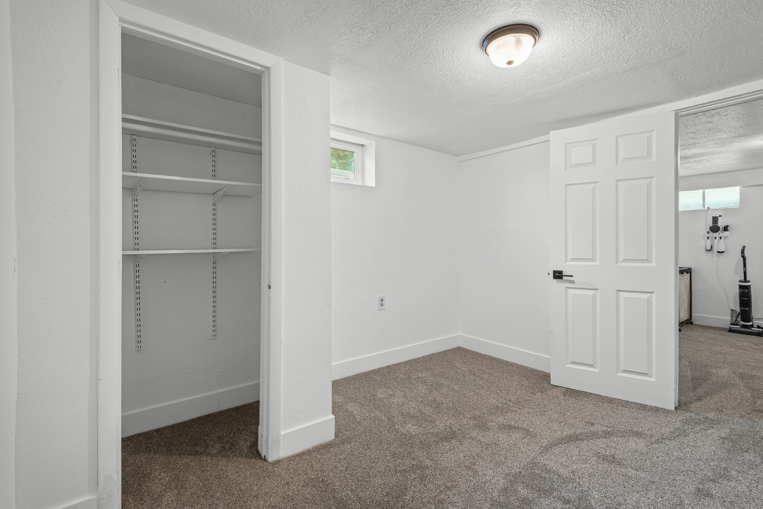 Room featuring neutral-tone carpeting, white walls, and a window for natural light