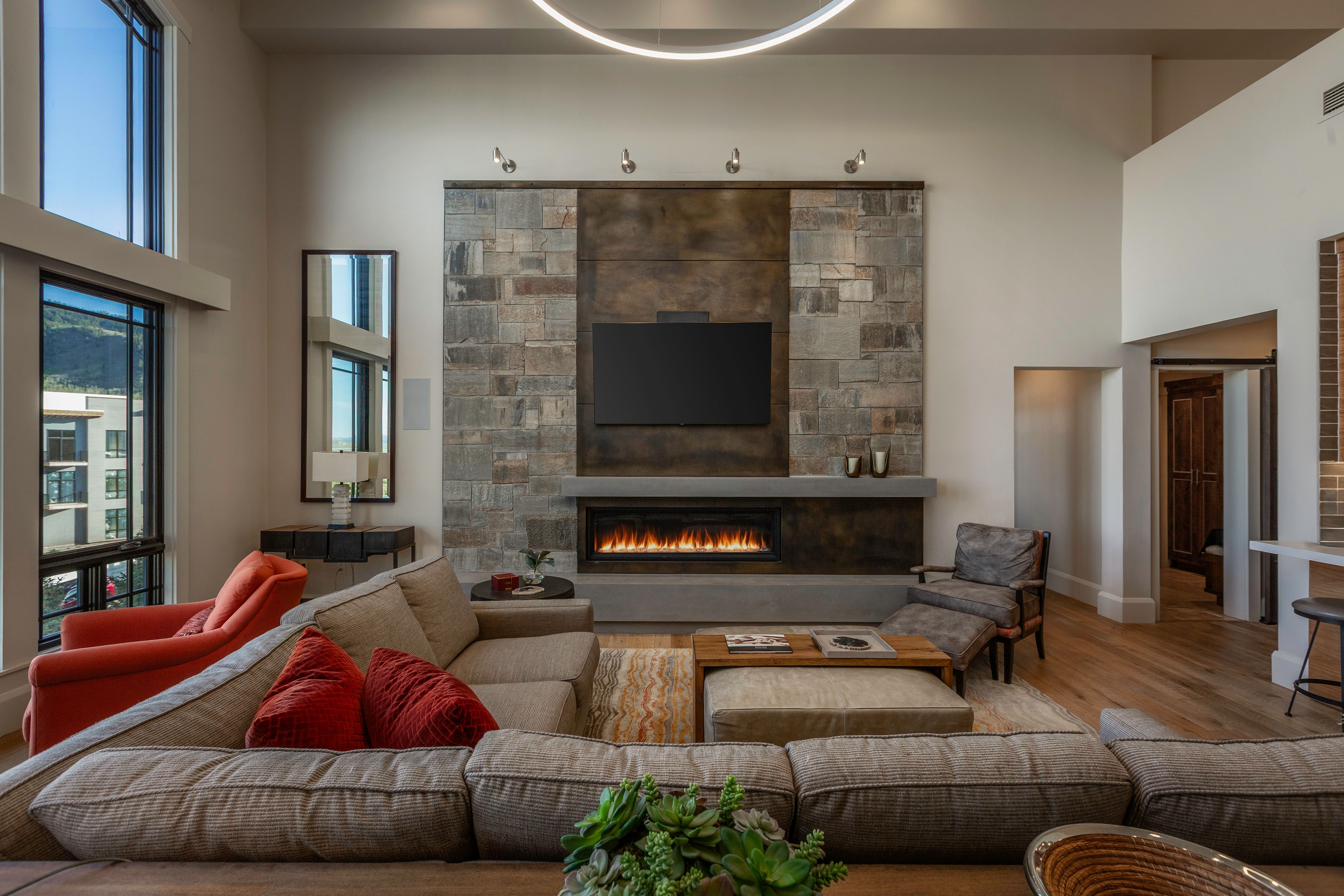 Contemporary living space featuring a floor-to-ceiling stone and dark panel fireplace surround with an integrated linear firebox