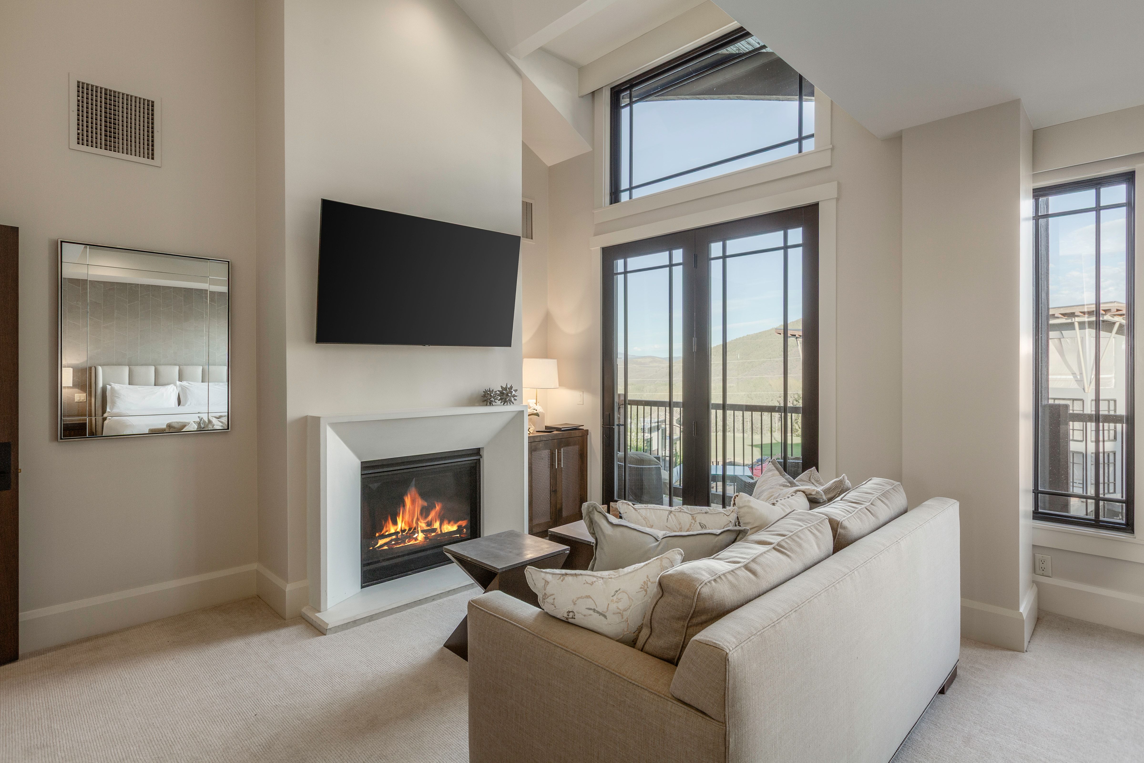 Vaulted ceilings featuring a recessed light fixture, a fireplace with a white surround, and an integrated wall-mounted television