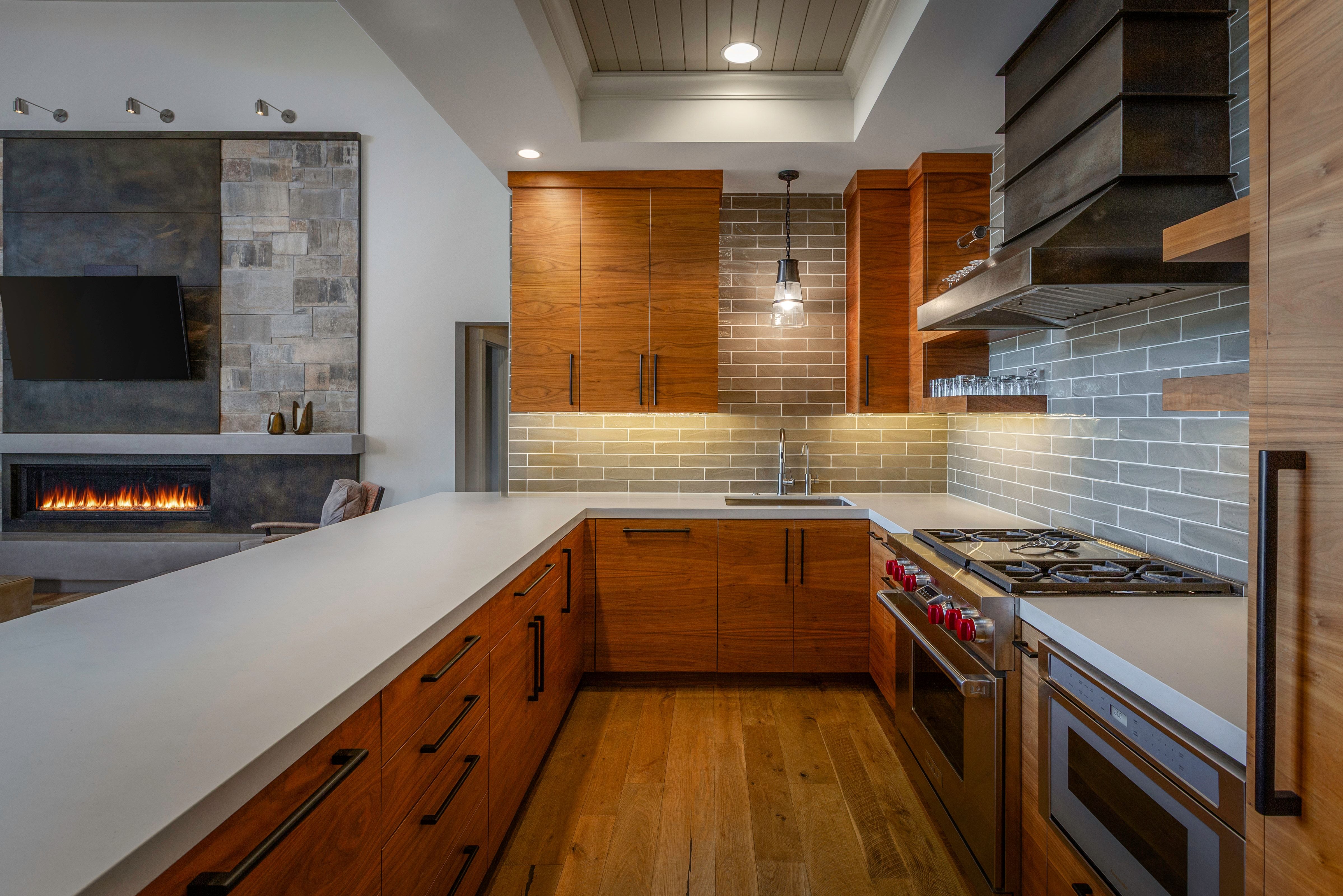 Open concept kitchen featuring wood cabinetry with integrated hardware, light gray subway tile backsplash, and a stainless steel professional-grade range