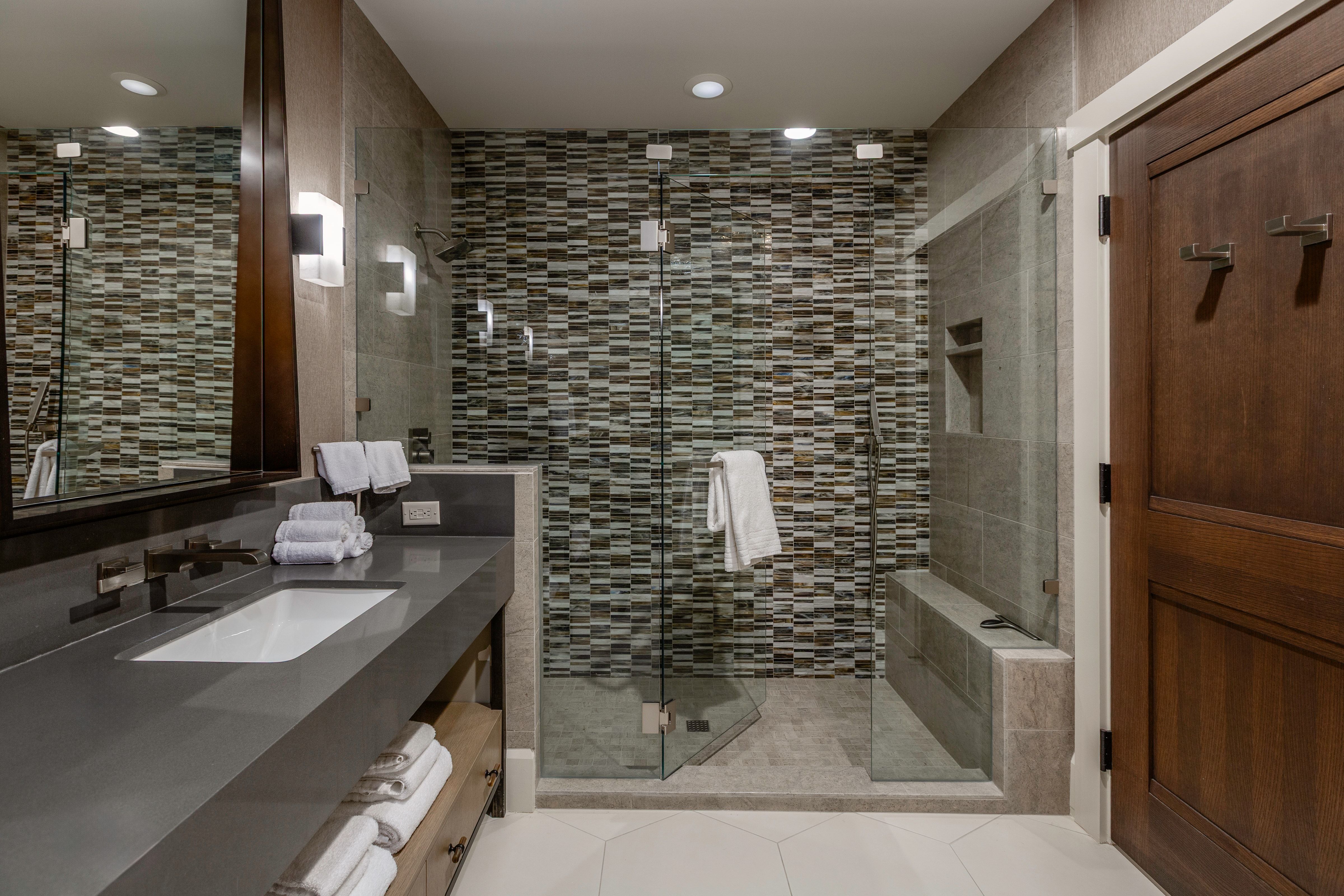 Bathroom featuring a glass-enclosed shower with mosaic tile detailing, a built-in shower bench, and a recessed niche