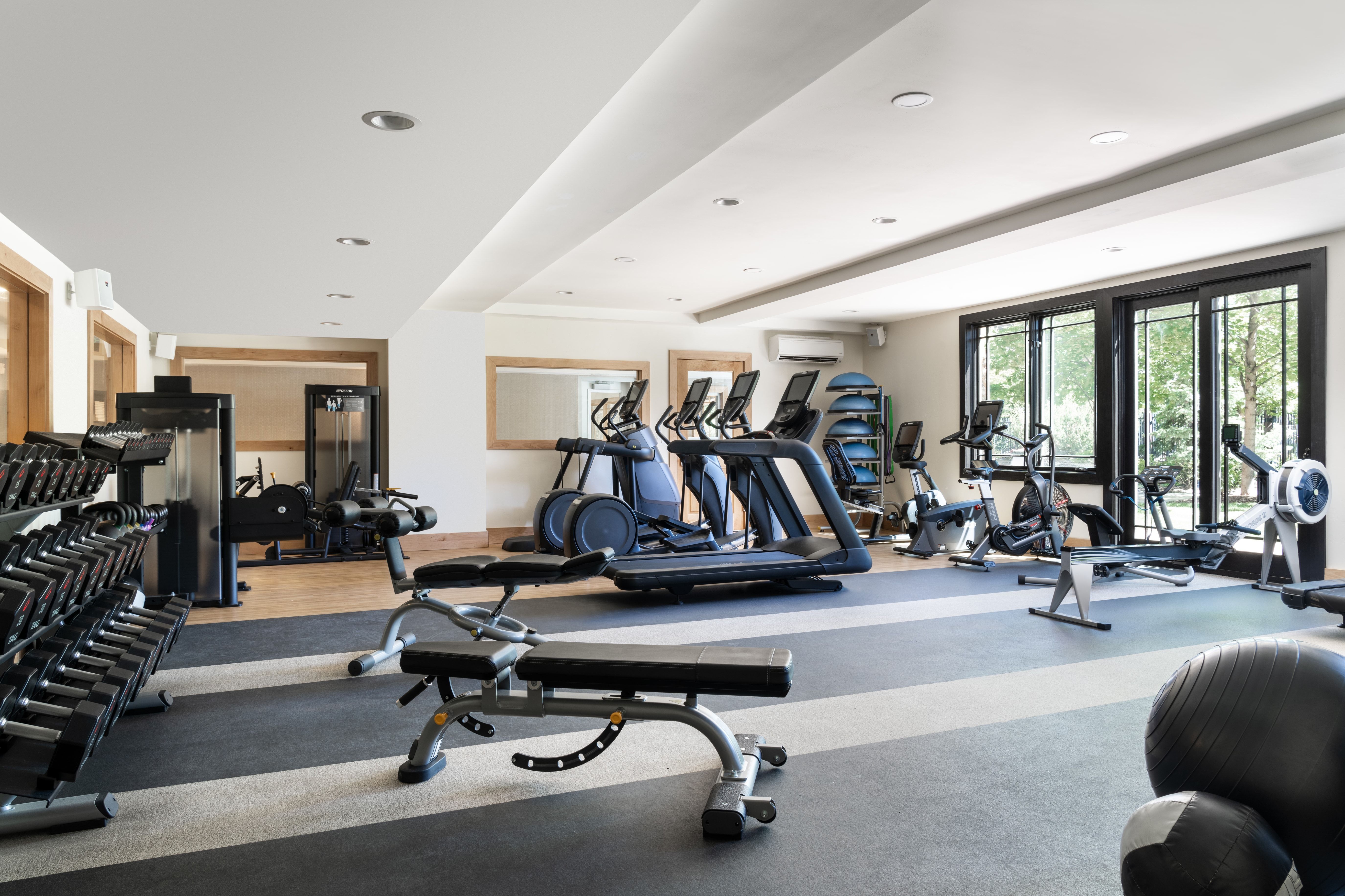 Dedicated fitness space featuring rubber flooring, recessed lighting, expansive windows, and a mirrored wall