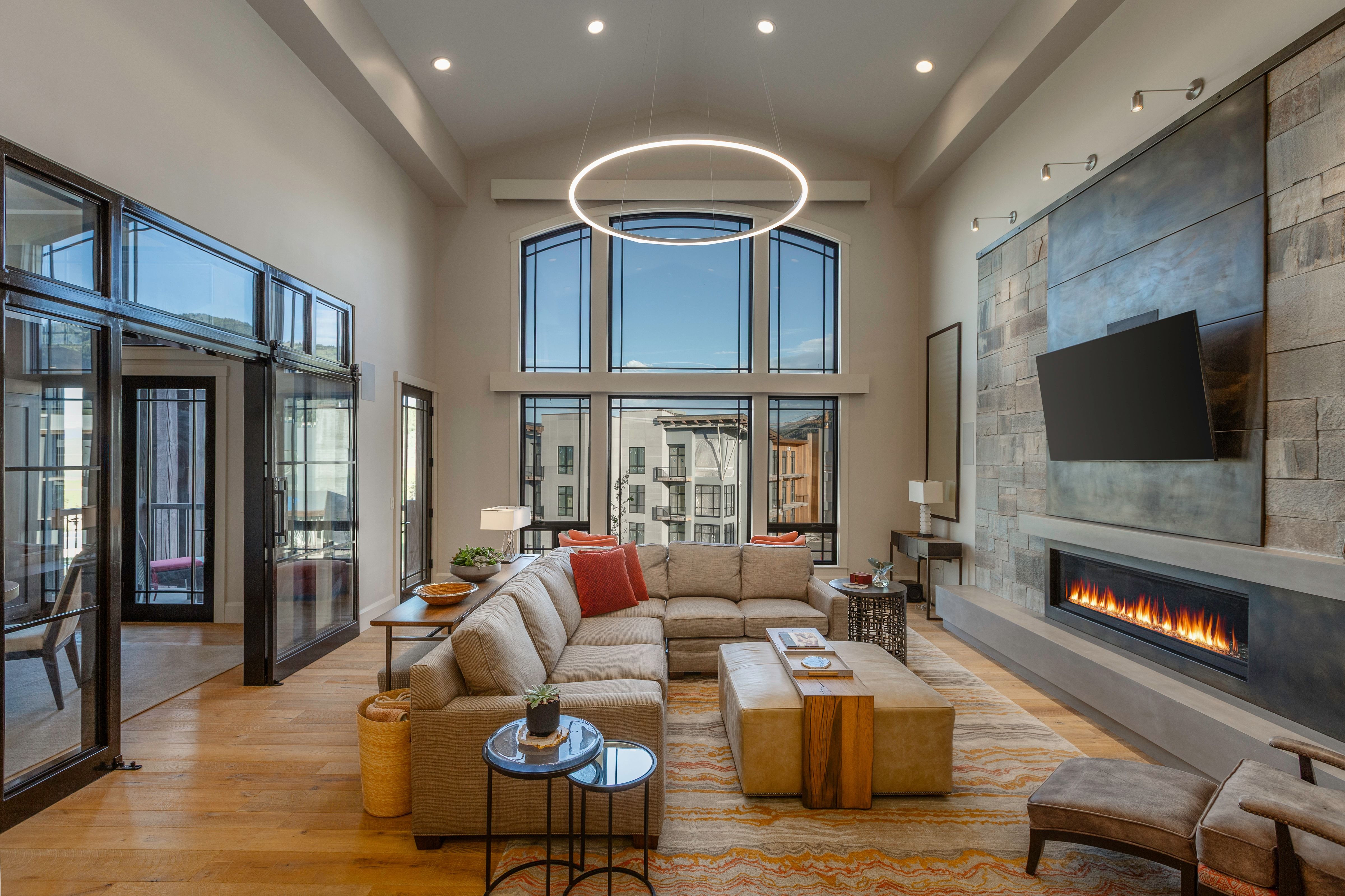 Vaulted living space with a floor-to-ceiling fireplace featuring a stone and panel accent wall