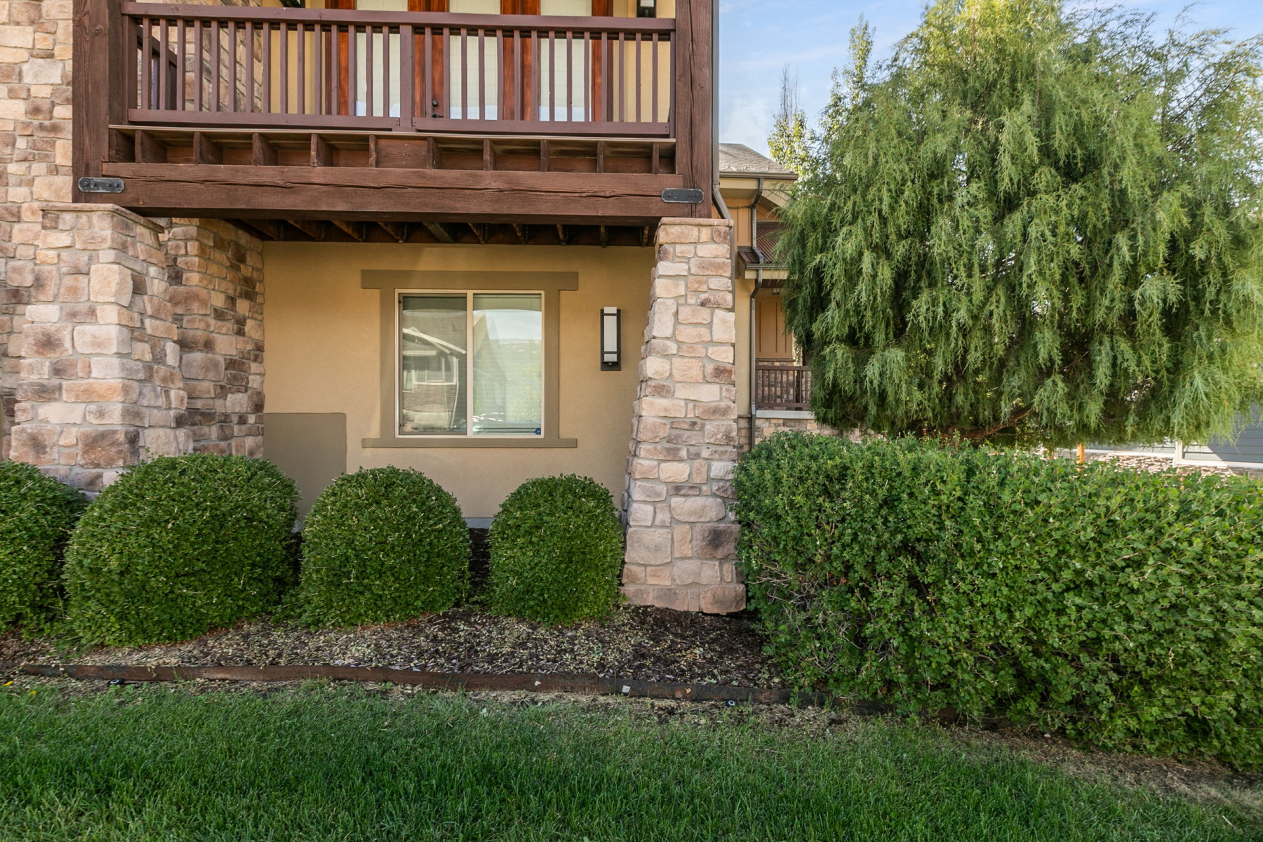 Stone veneer and stucco exterior with a second-story wooden balcony