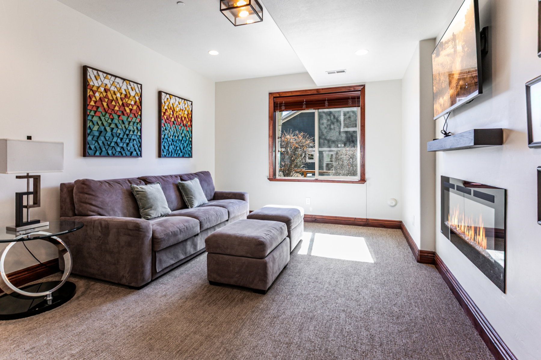 Carpeted living space featuring an electric fireplace with a wall-mounted display, a window with wood trim, recessed lighting, and a square ceiling fixture