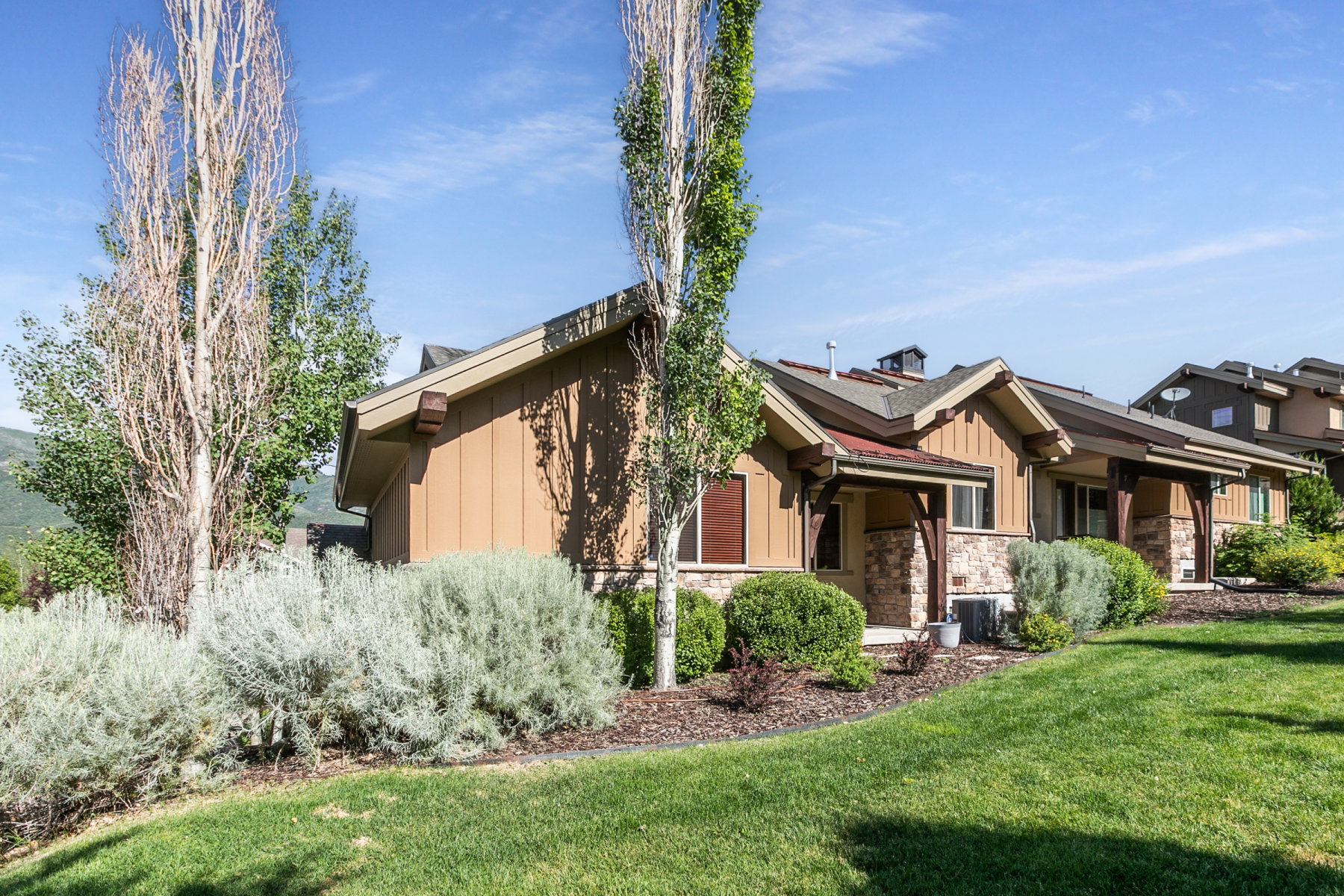 Exterior features include a peaked roofline, wood siding, and stone accents