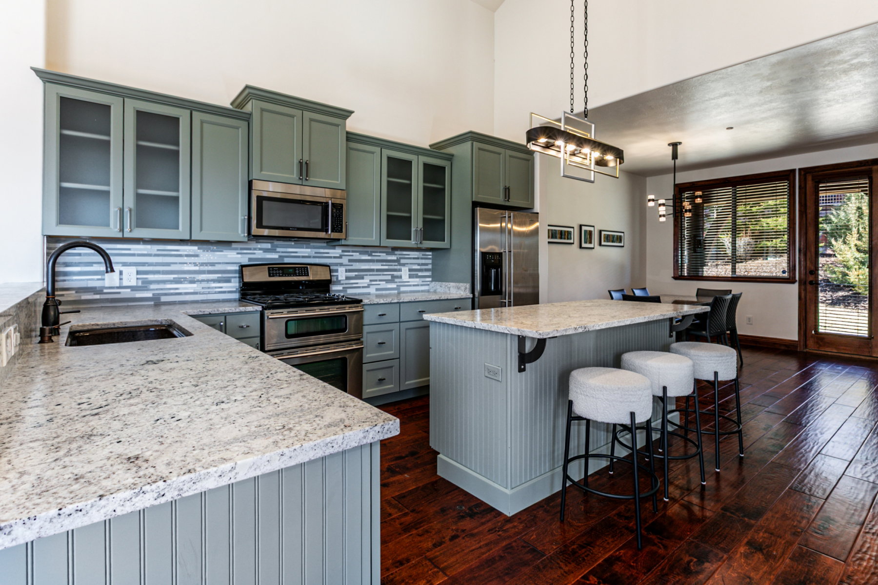 Kitchen featuring light gray cabinetry with frosted glass inserts, stainless steel appliances, and a mosaic tile backsplash