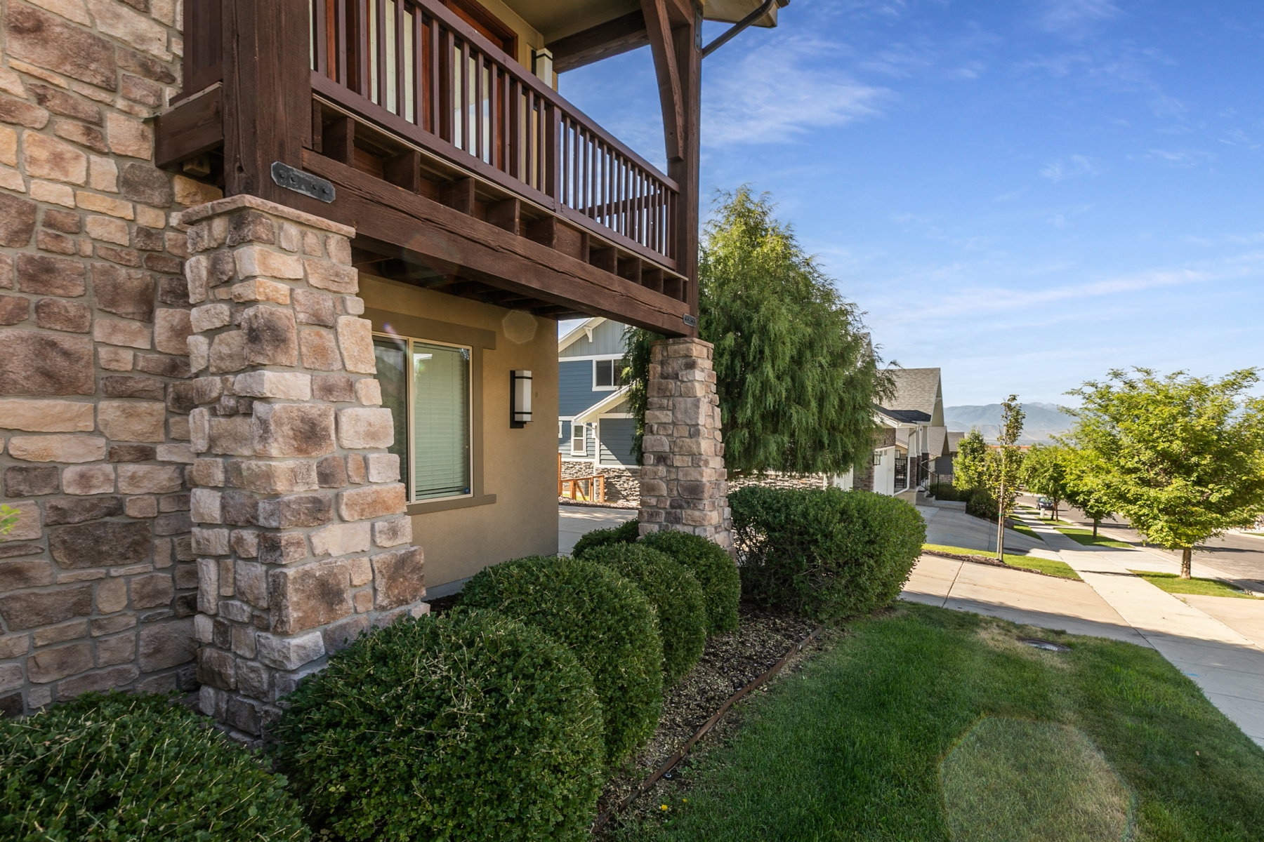Stone veneer facade with wood balcony featuring balusters