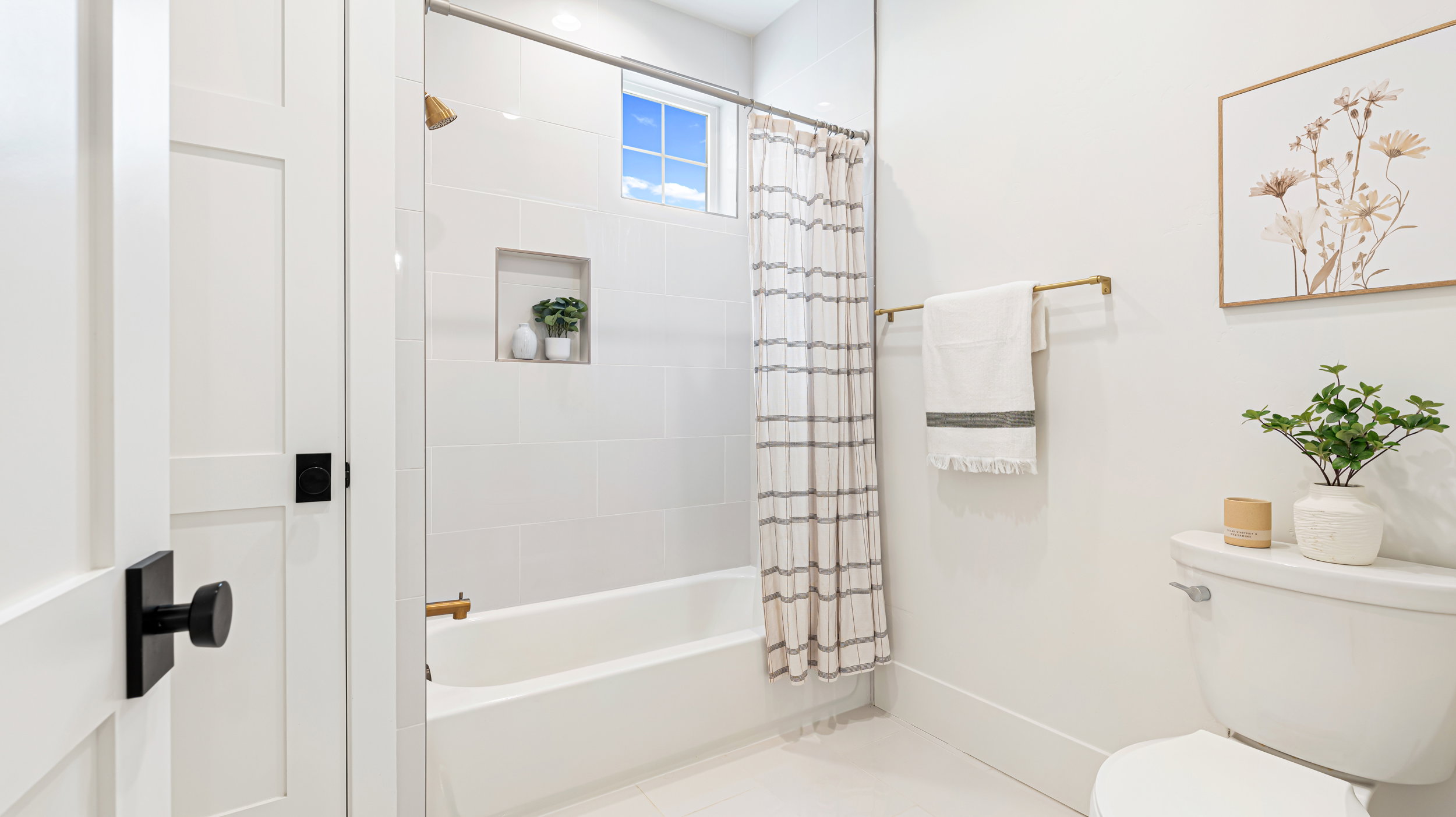 Bathroom featuring a white bathtub, tiled shower surround with built-in niche, and a window for natural light