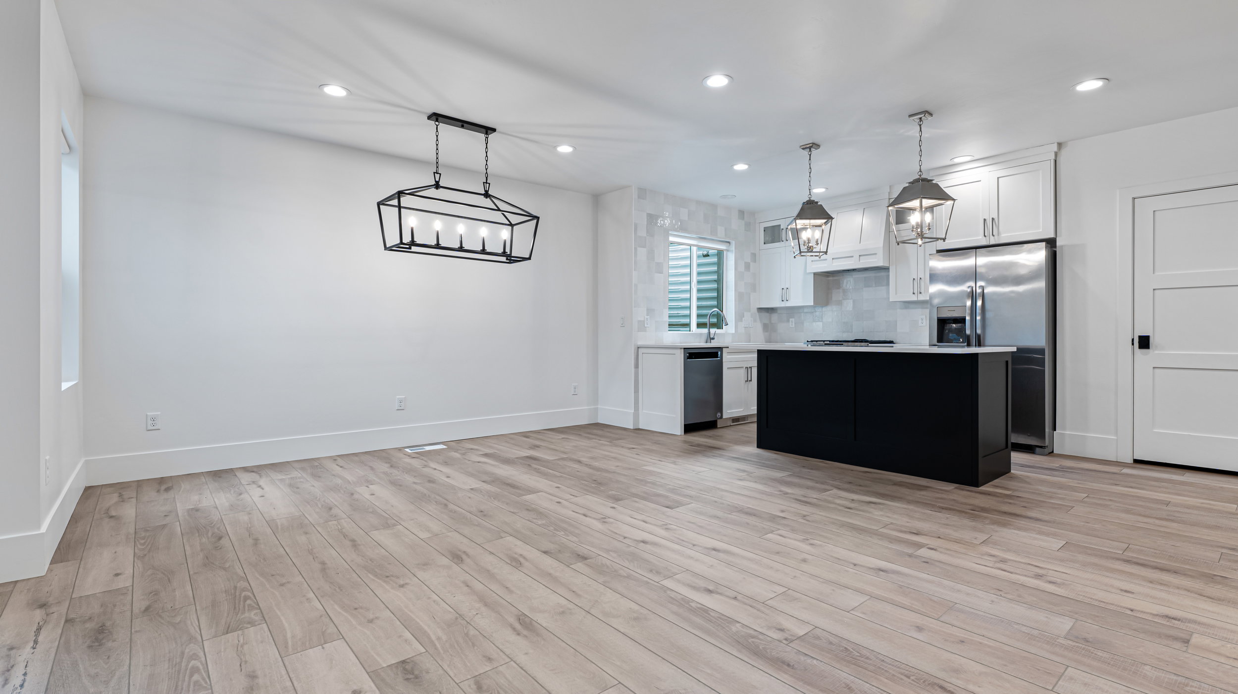 Open-concept living space featuring wood-finish flooring, recessed lighting, and a modern geometric chandelier