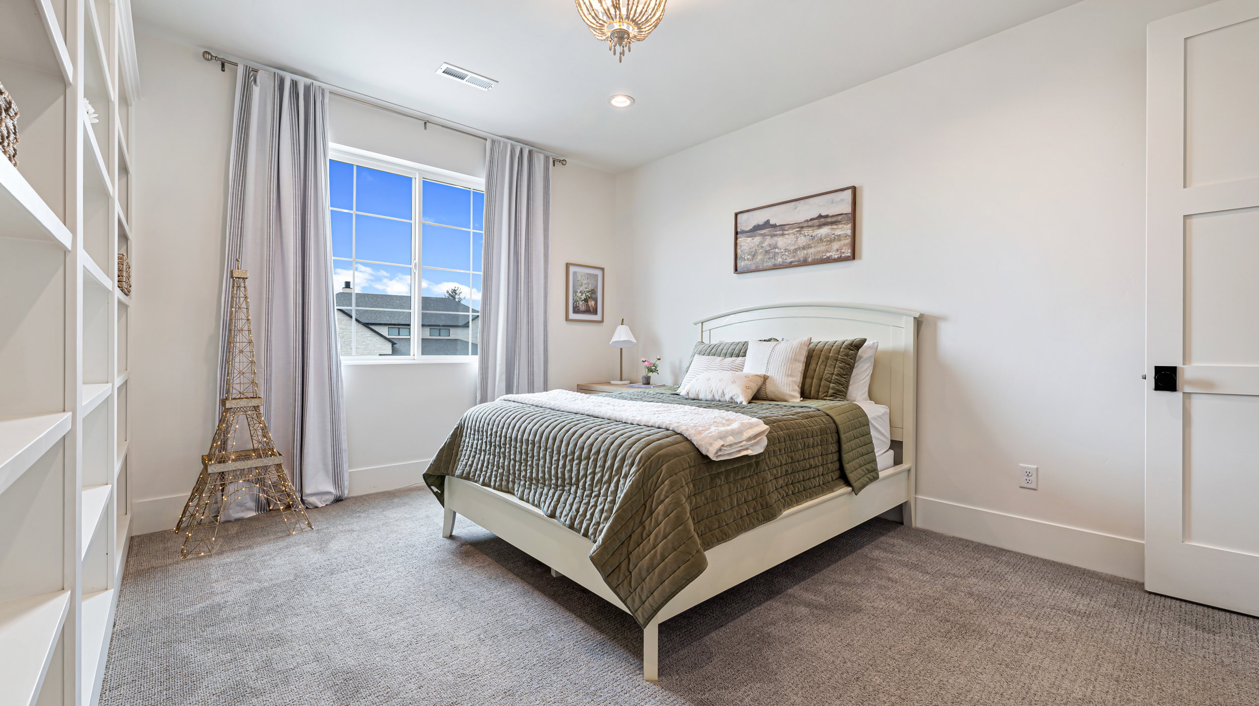 Well-lit room featuring a multi-pane window, neutral carpet, built-in shelving, and a modern paneled door with a matte black handle