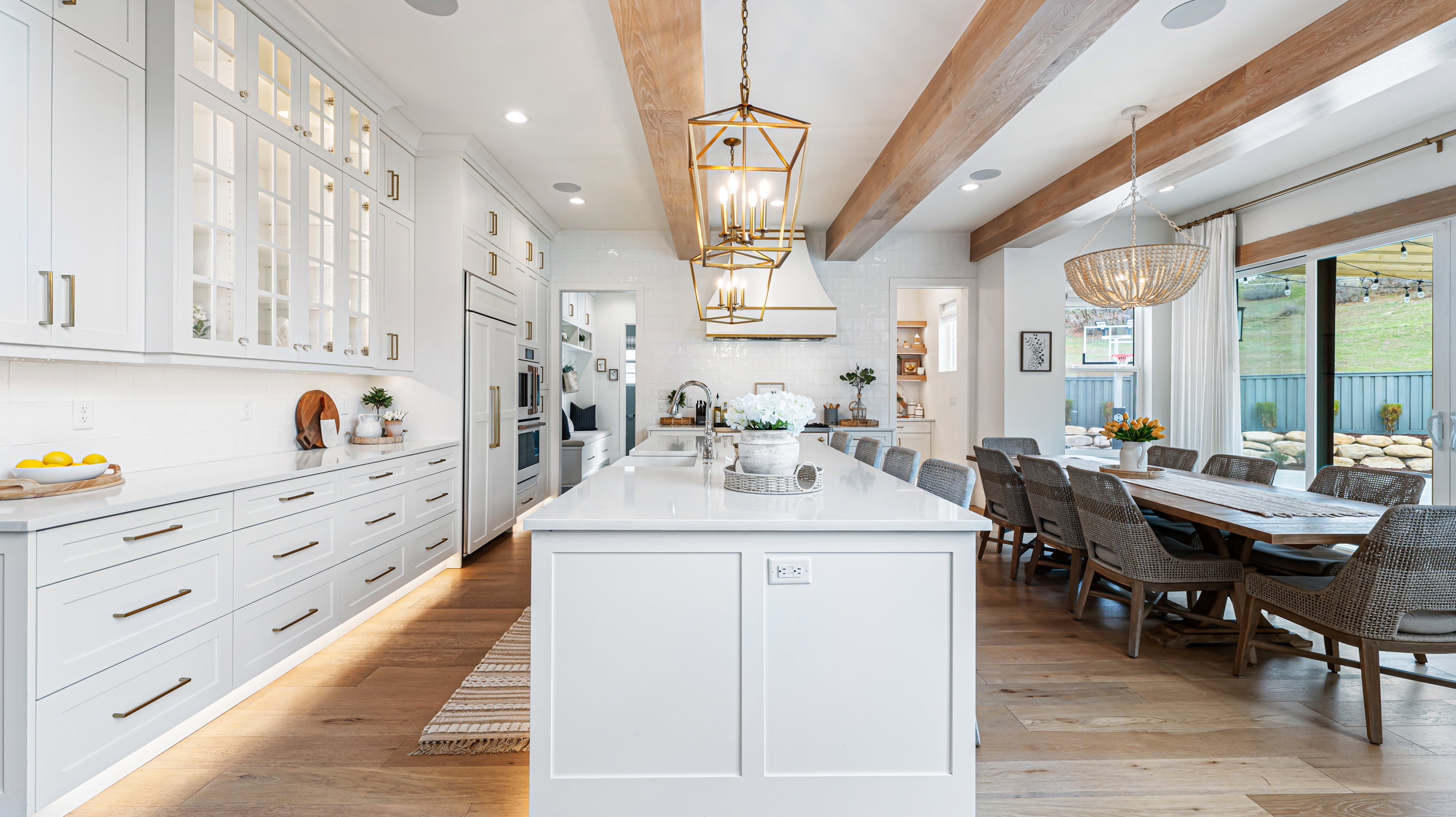 Spacious kitchen and dining area featuring light wood-finish flooring, white cabinetry with integrated appliances, and a substantial island with countertop seating