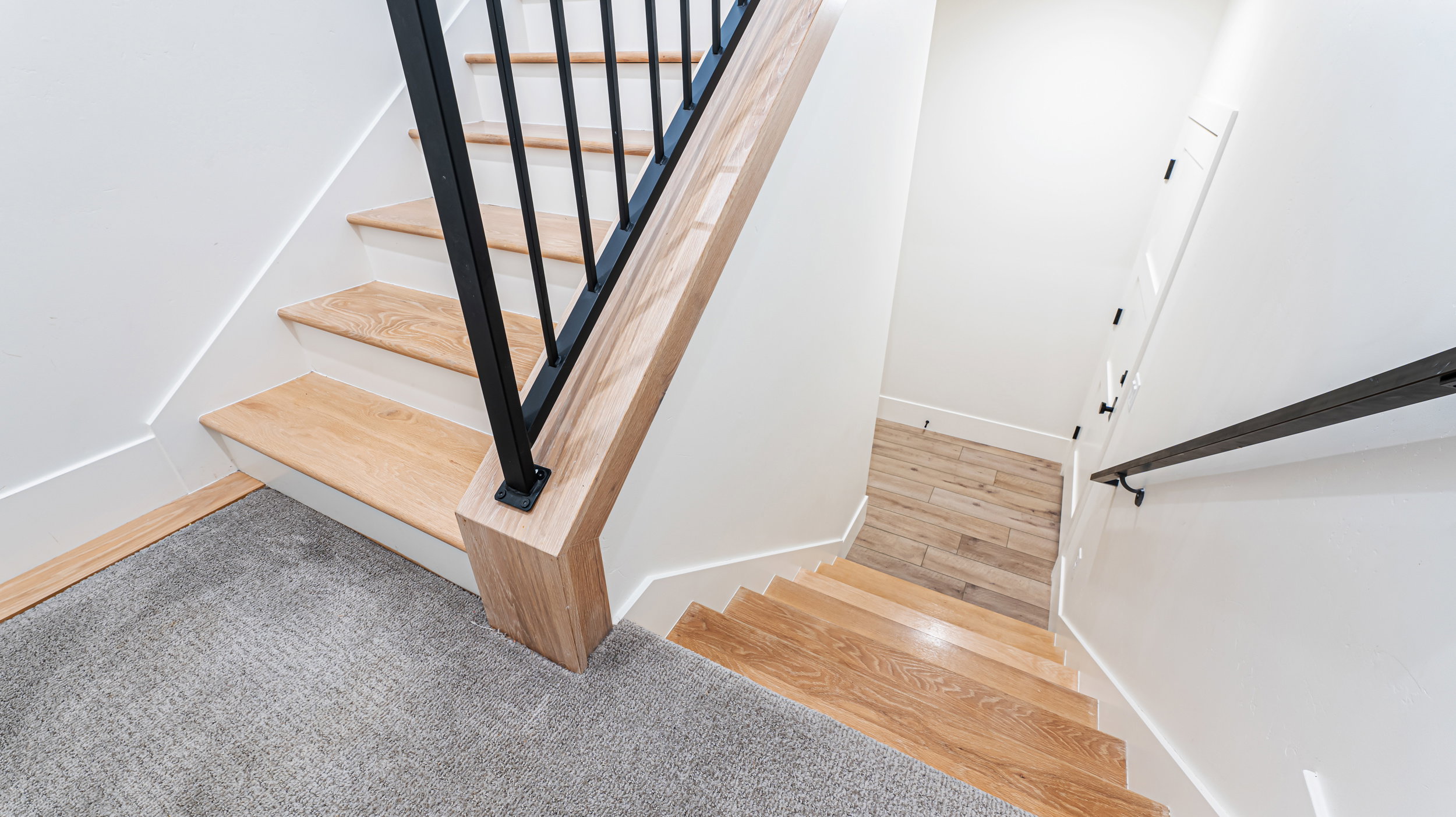 Staircase featuring wood-finish treads, white risers, and a black metal railing