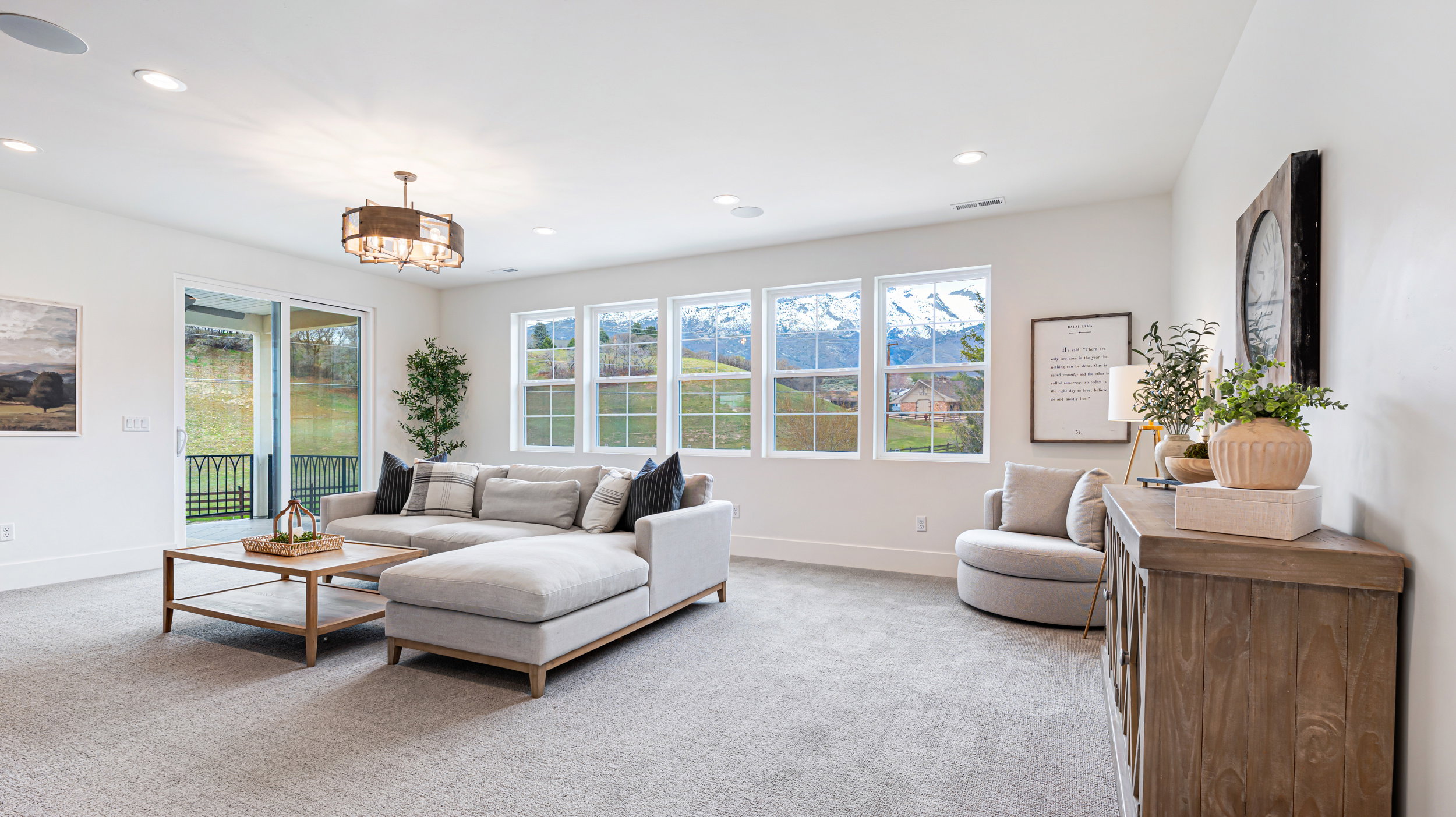 Spacious living area featuring light gray carpeting, recessed lighting, and a contemporary chandelier