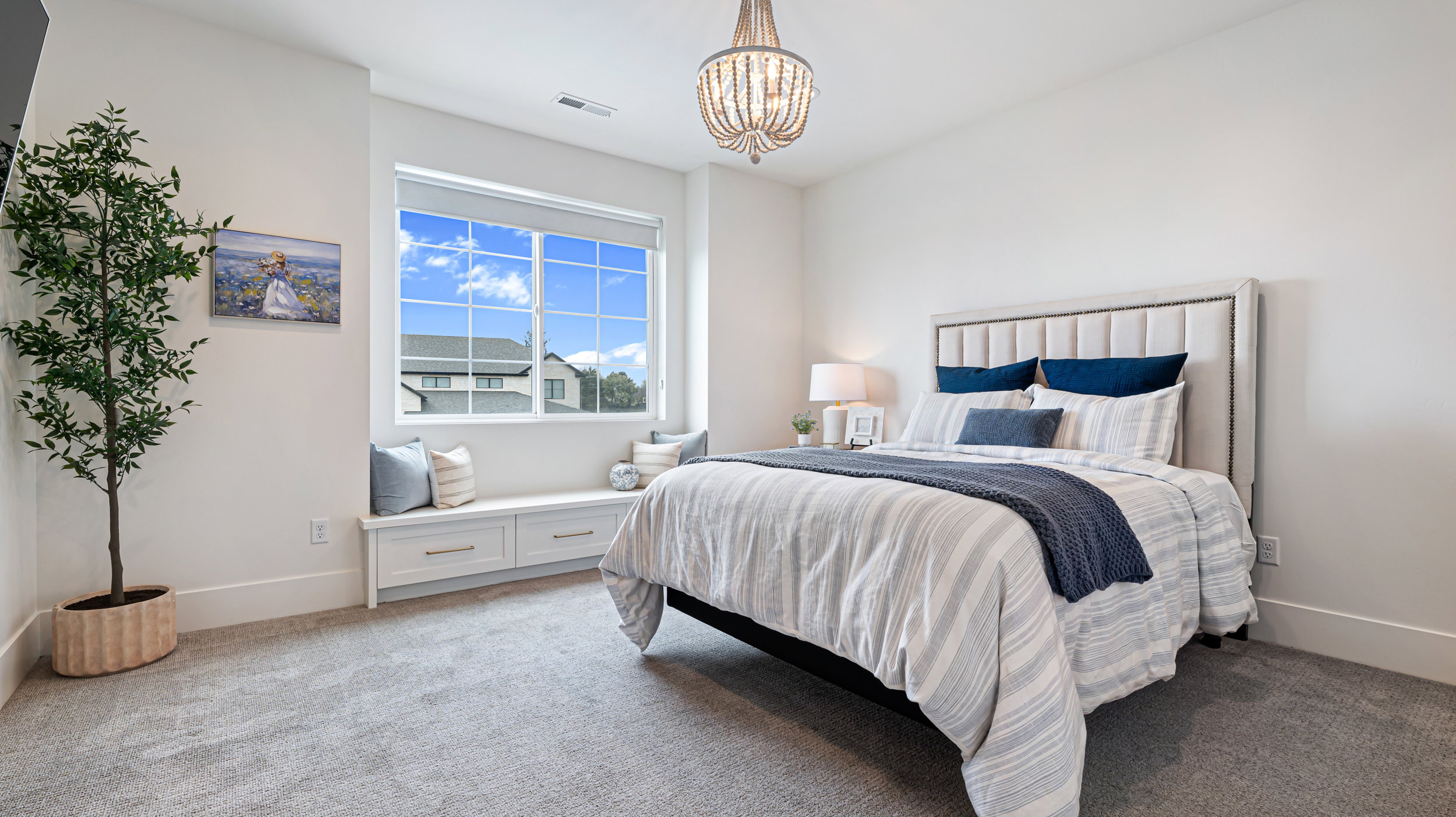 Bedroom featuring light gray carpeting, a built-in window bench with storage drawers, and a beaded chandelier