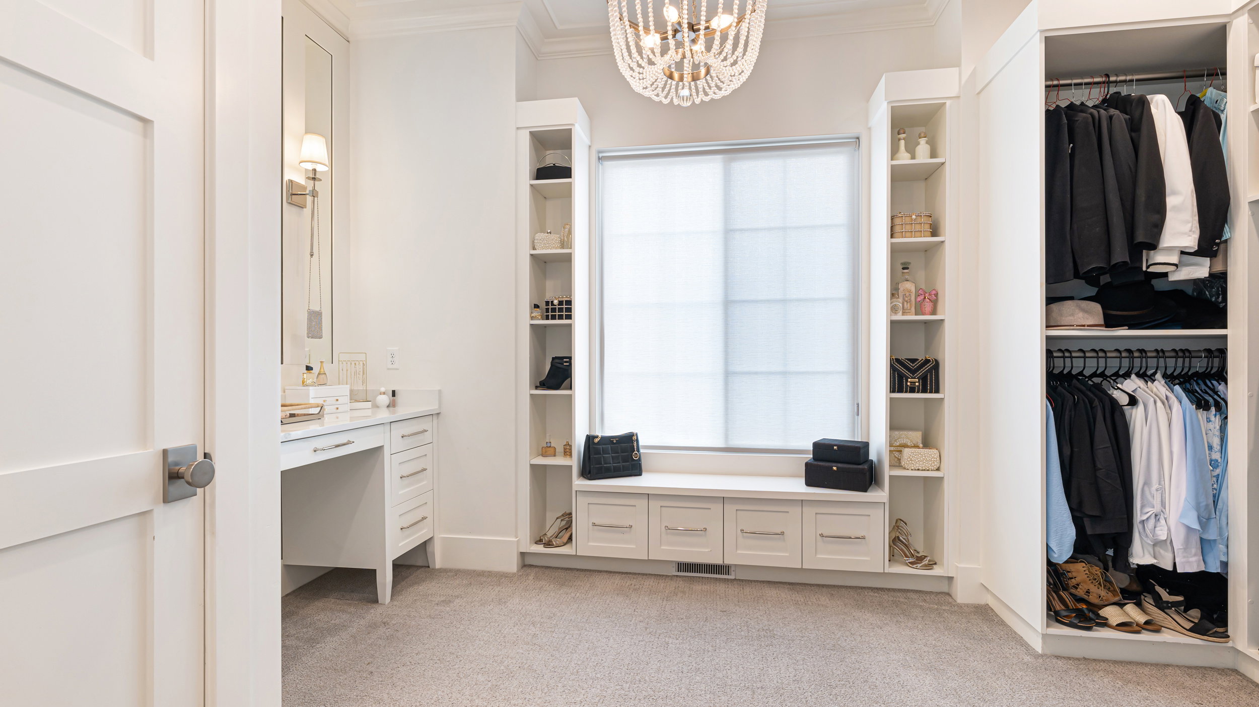 Walk-in closet with built-in cabinetry, window seating, and a crystal chandelier