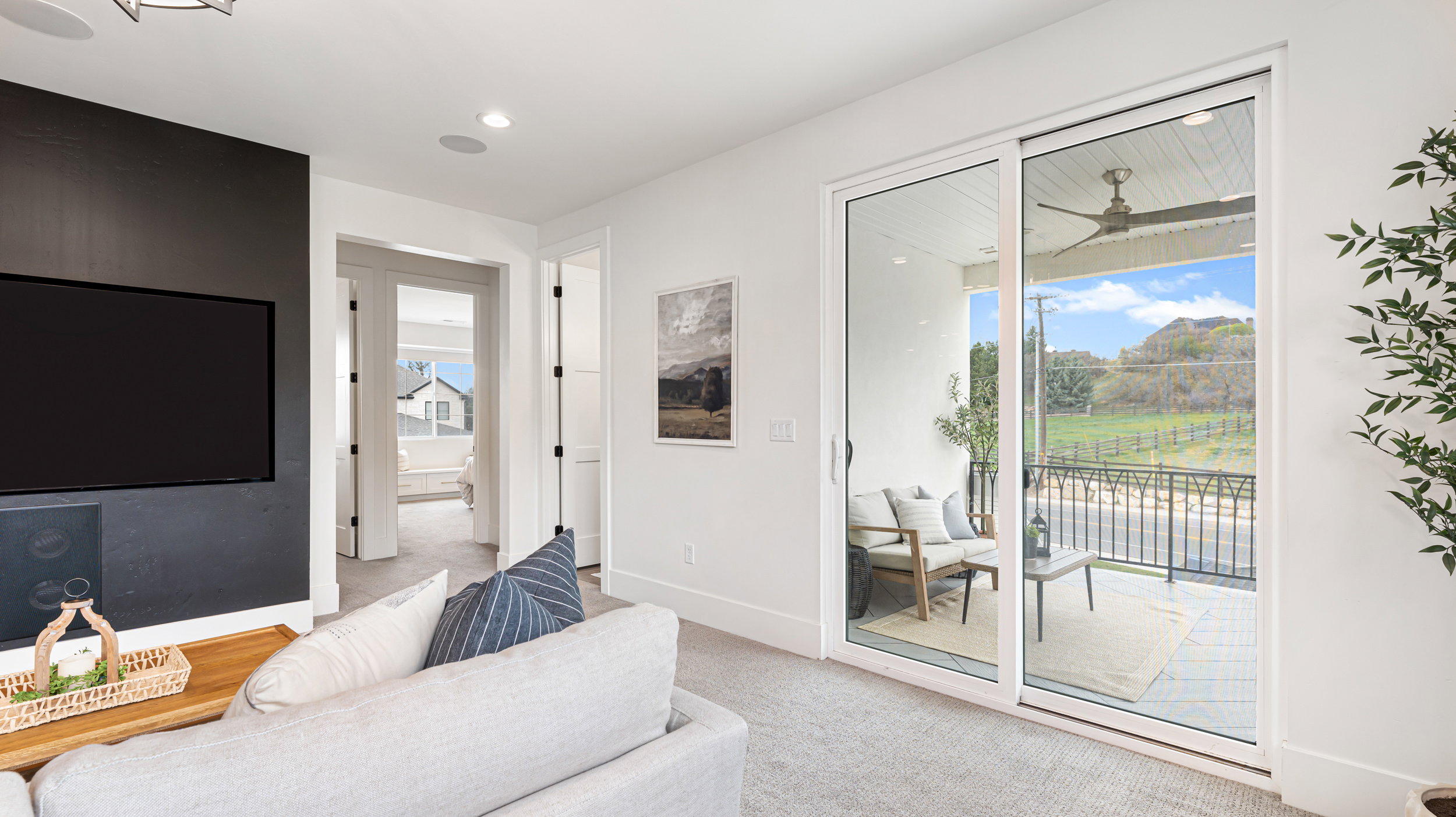 Spacious interior featuring white walls, recessed lighting, and a large sliding glass door opening to an outdoor balcony