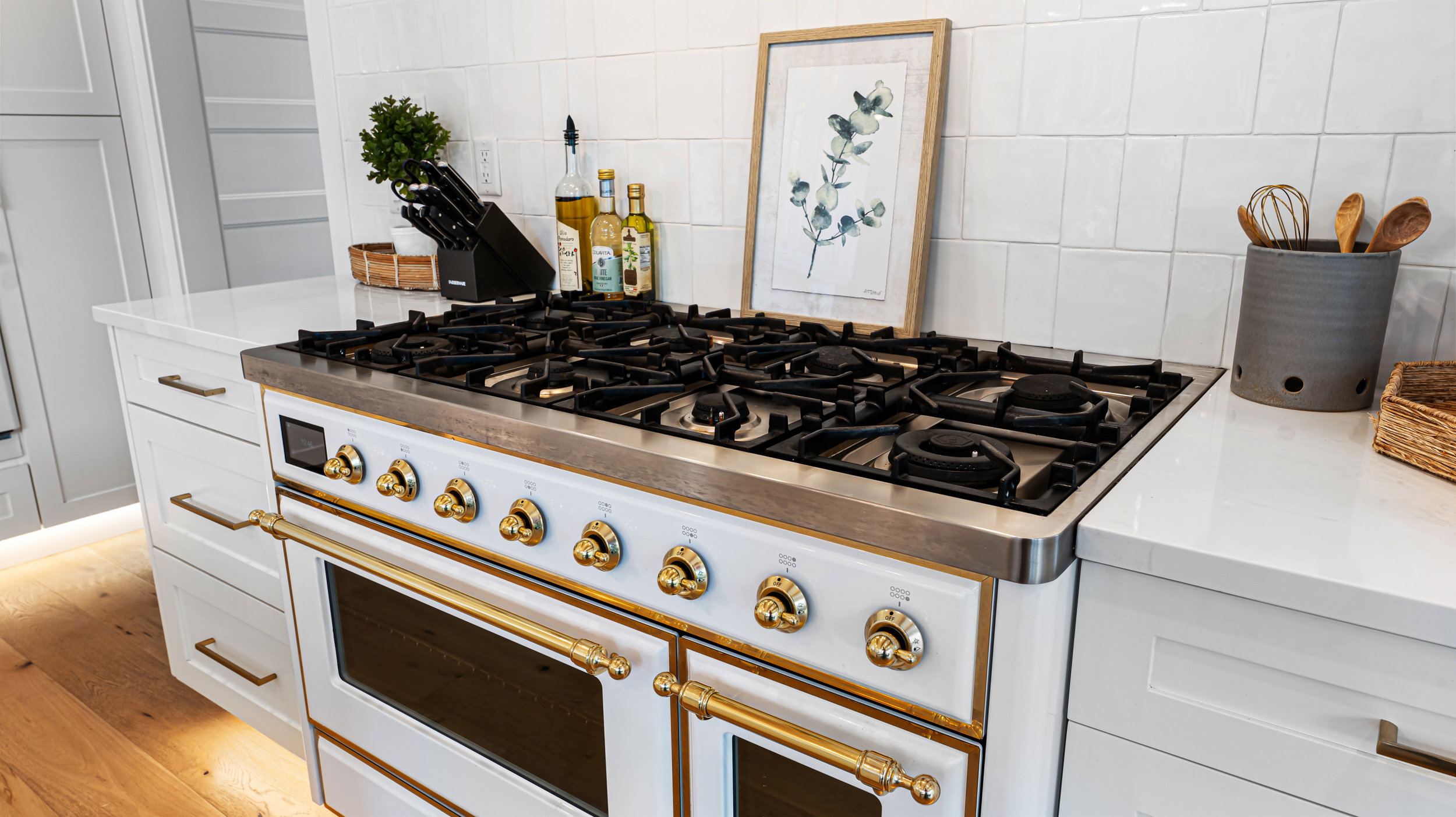 Professional-grade gas range with brass accents set against white subway tile backsplash