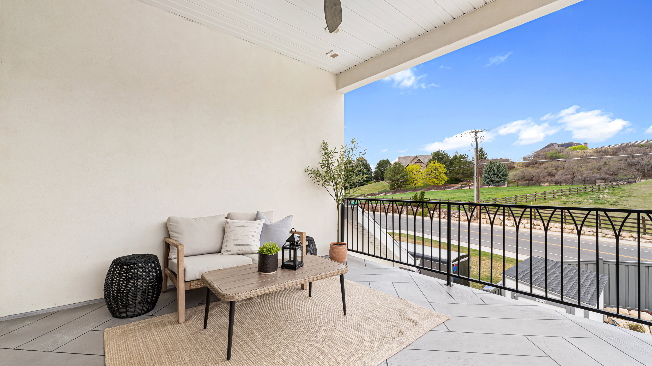 Covered outdoor balcony featuring light-toned stucco walls and a white slatted ceiling