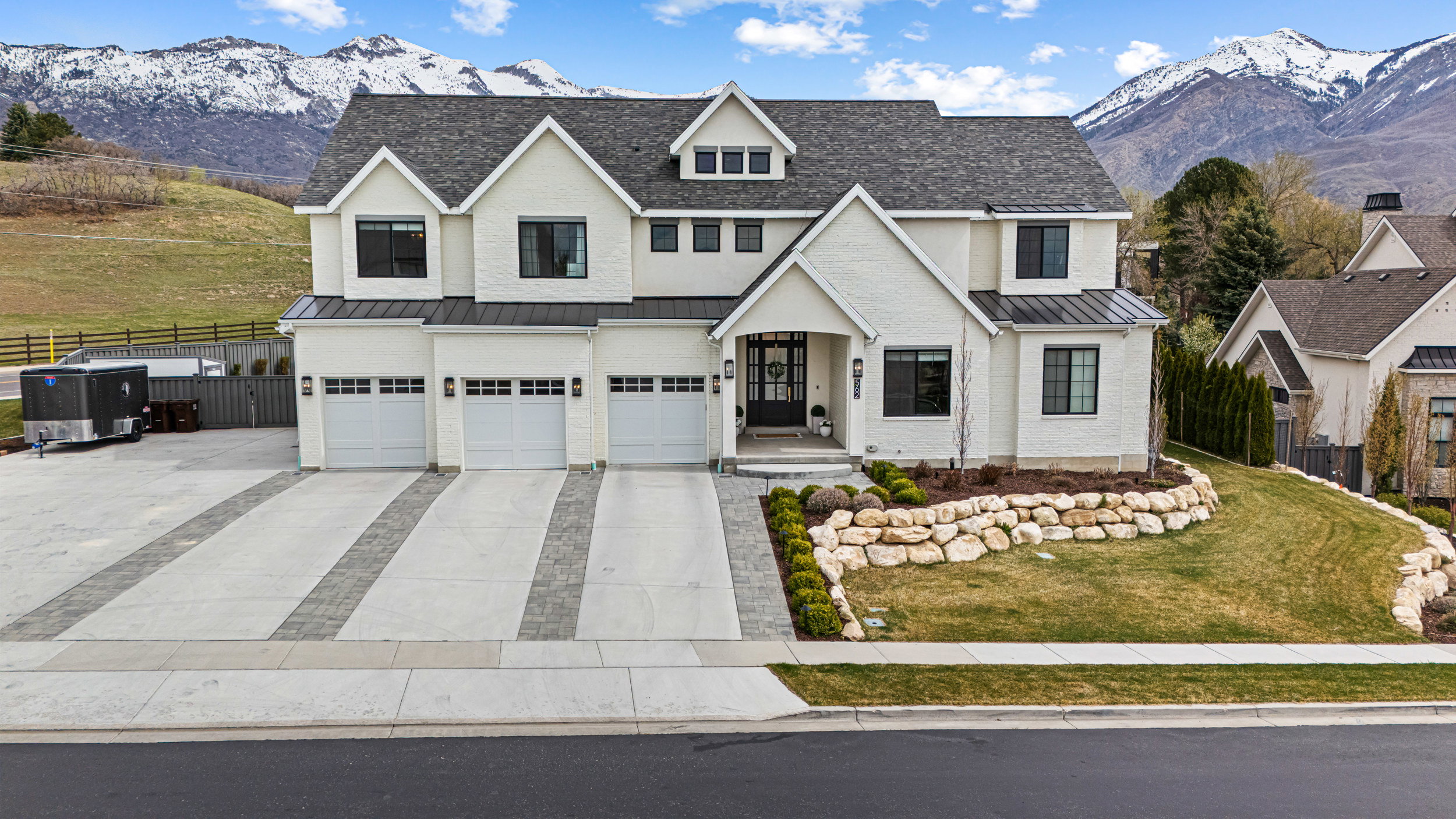 Modern Colonial-style residence featuring a white brick exterior, dark window frames, and a prominent three-car garage