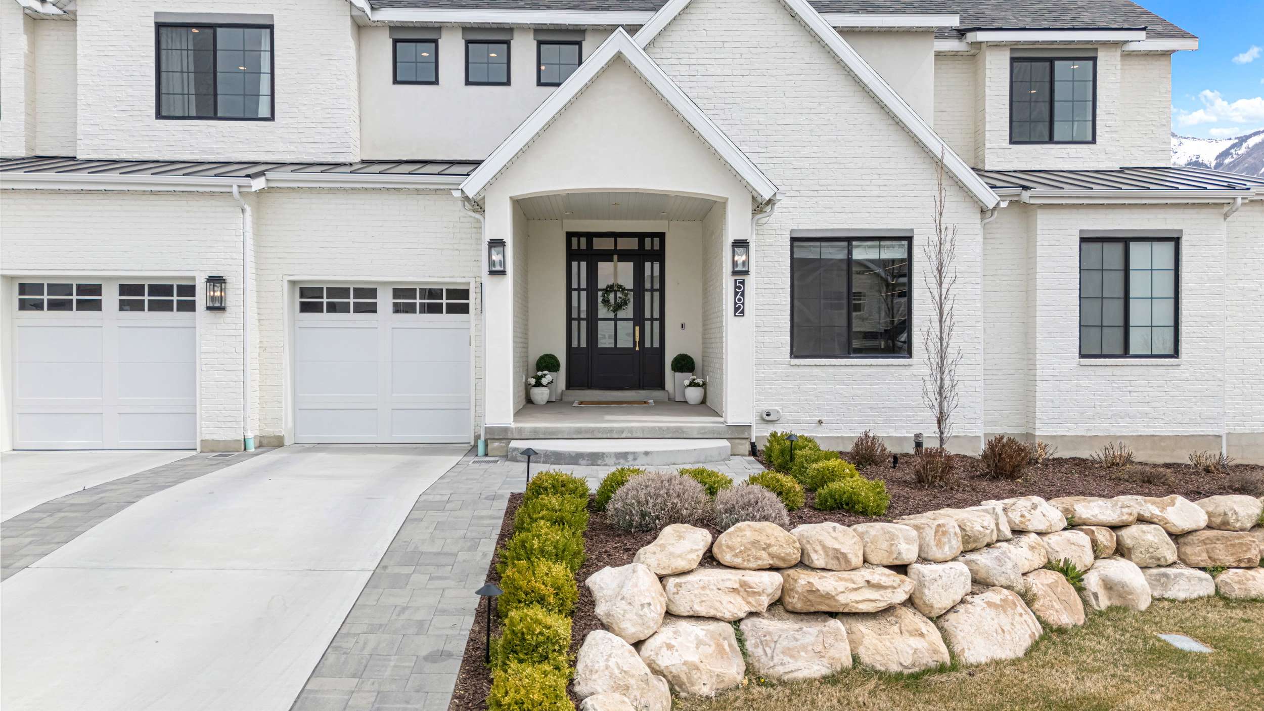 Contemporary white brick exterior with black-framed windows and a prominent gabled entry