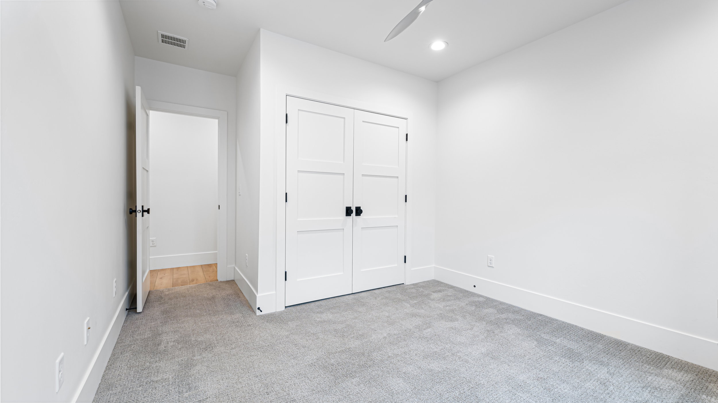 Neutral gray carpeting with white baseboards, white walls, and a white ceiling