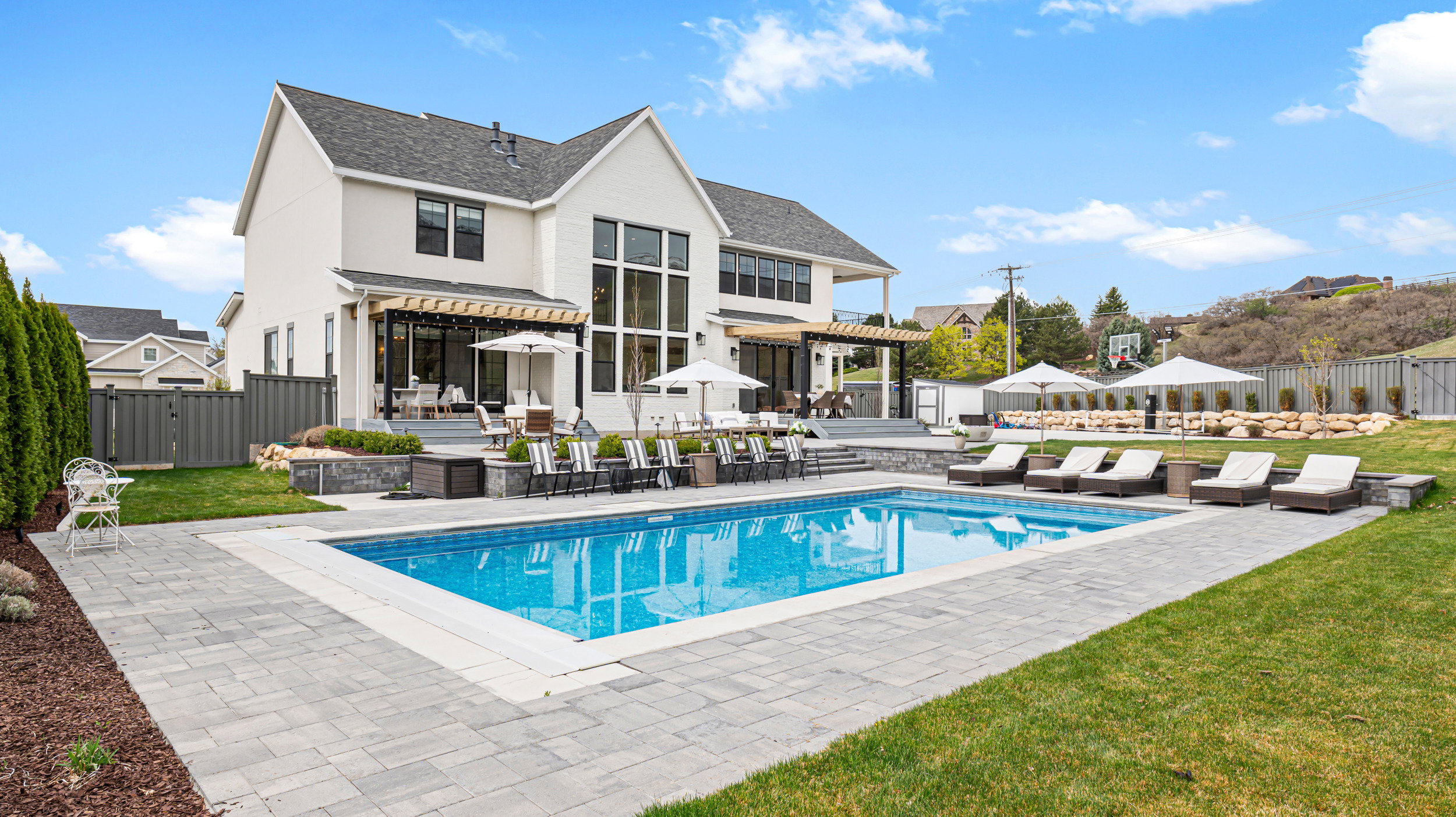 Rectangular in-ground pool surrounded by paver patio and lawn