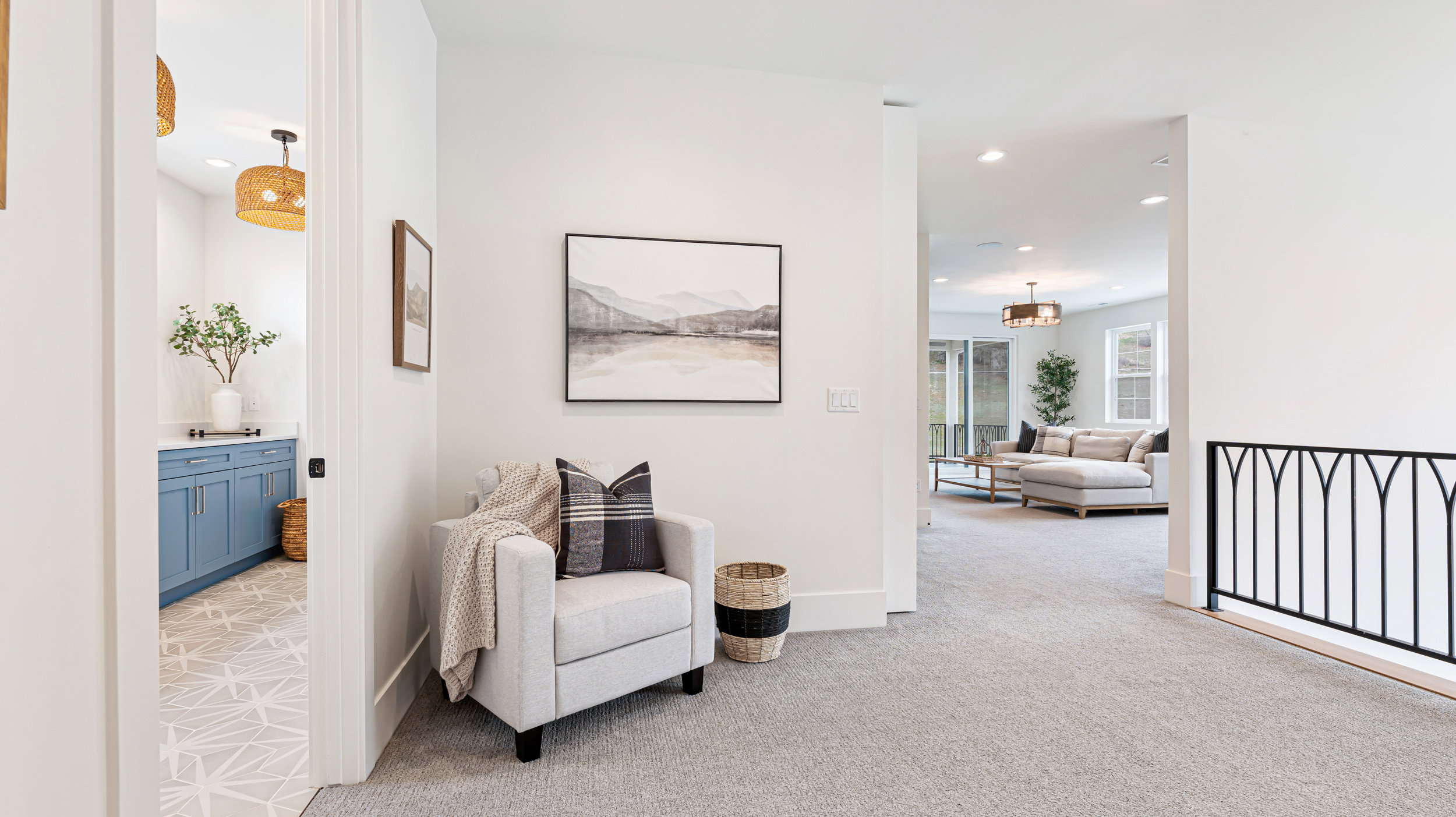 Carpeted hallway with a black metal railing and recessed lighting