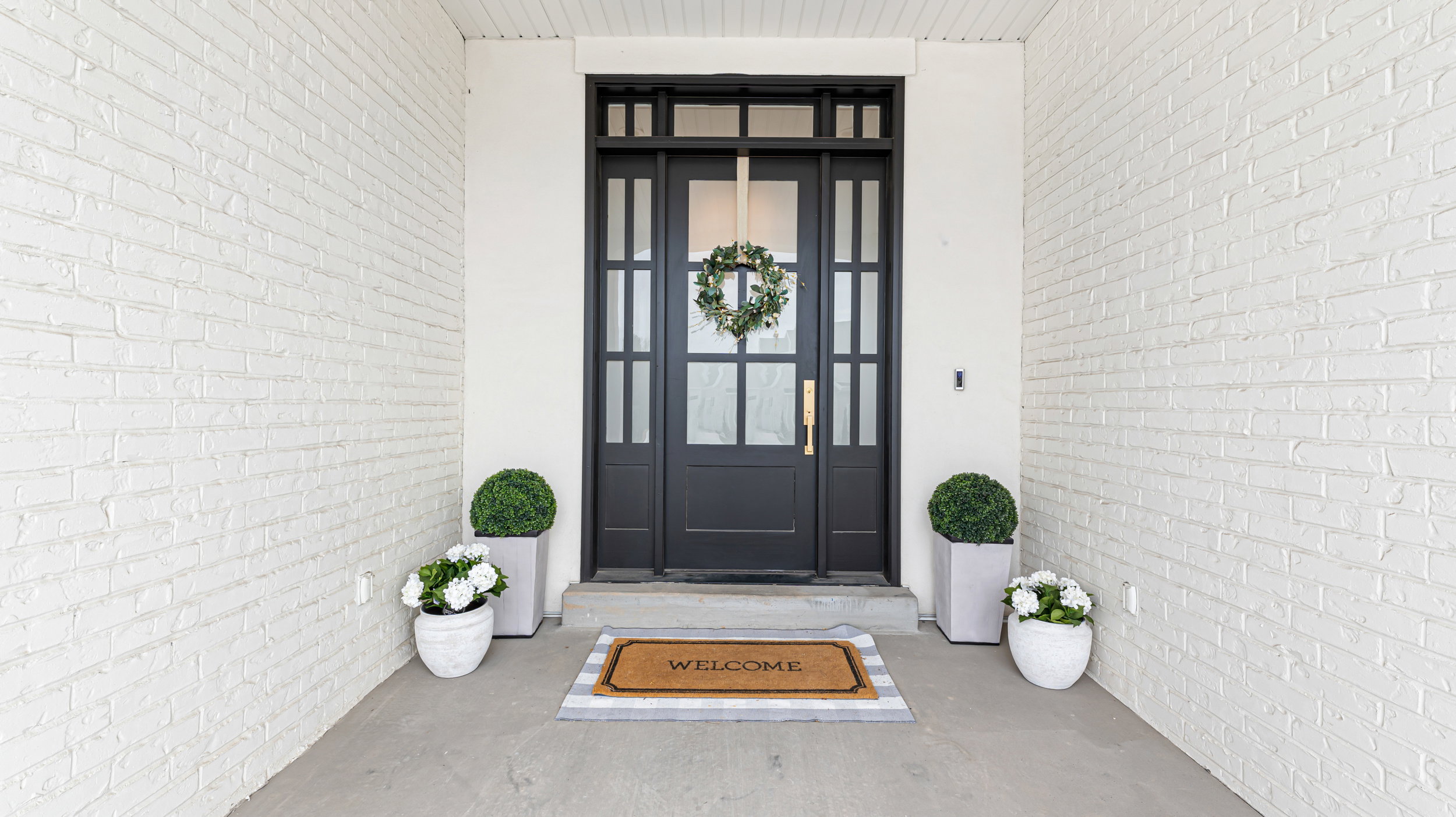 Entryway featuring a solid black door with clear glass panels, a transom window, and sidelights