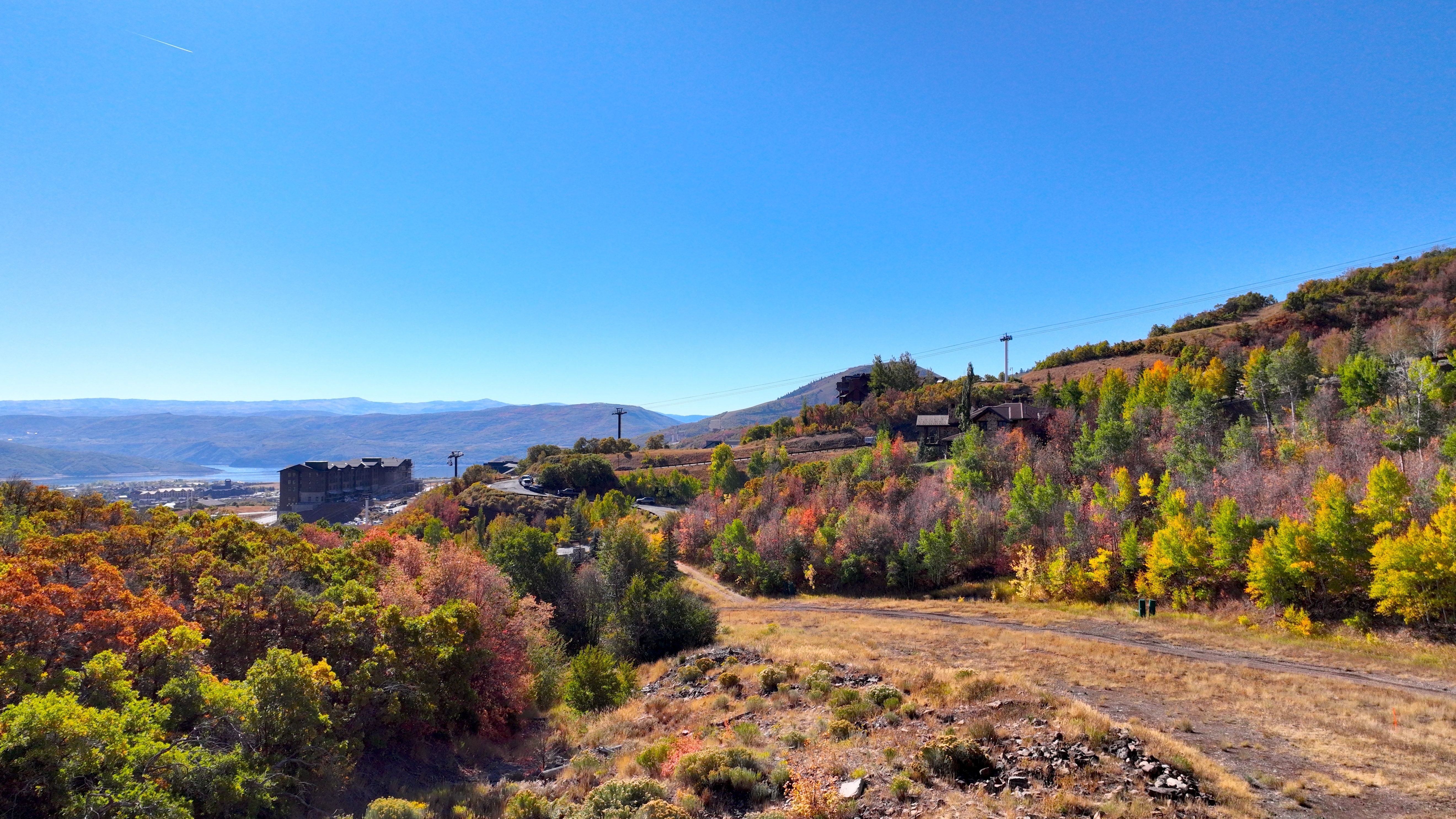 Expansive mountain landscape featuring vibrant autumn foliage and distant mountain ranges
