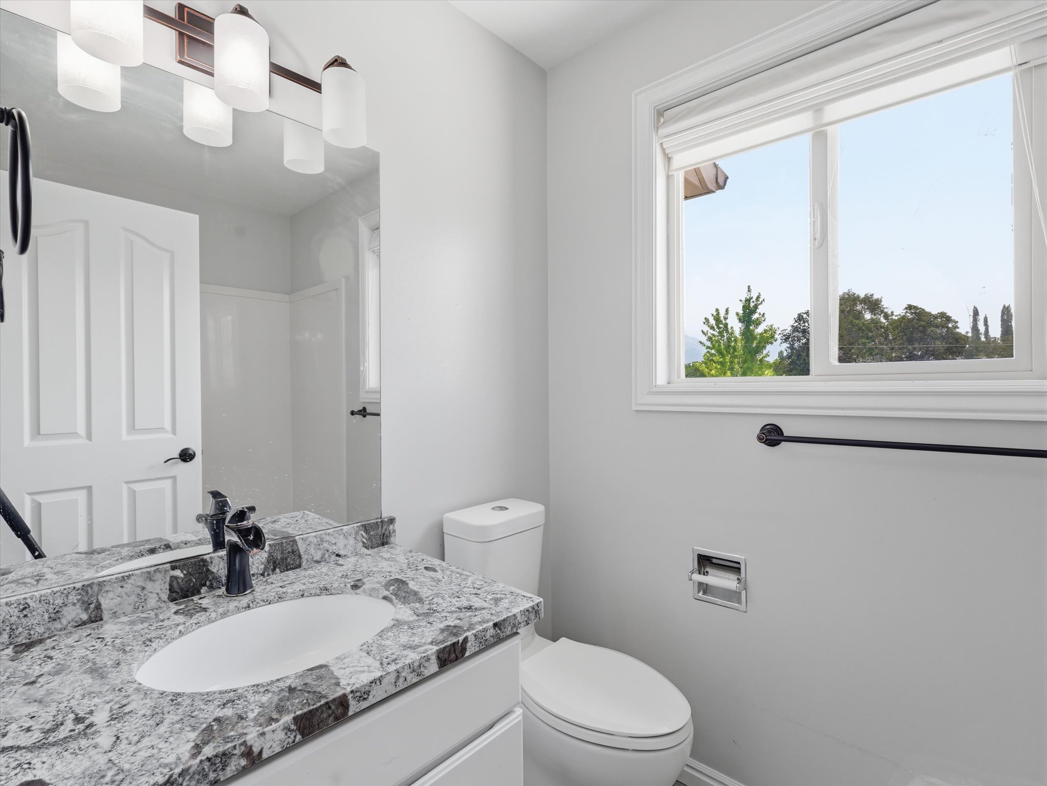 Bathroom featuring a granite-finish vanity, undermount sink, and black-finish faucet