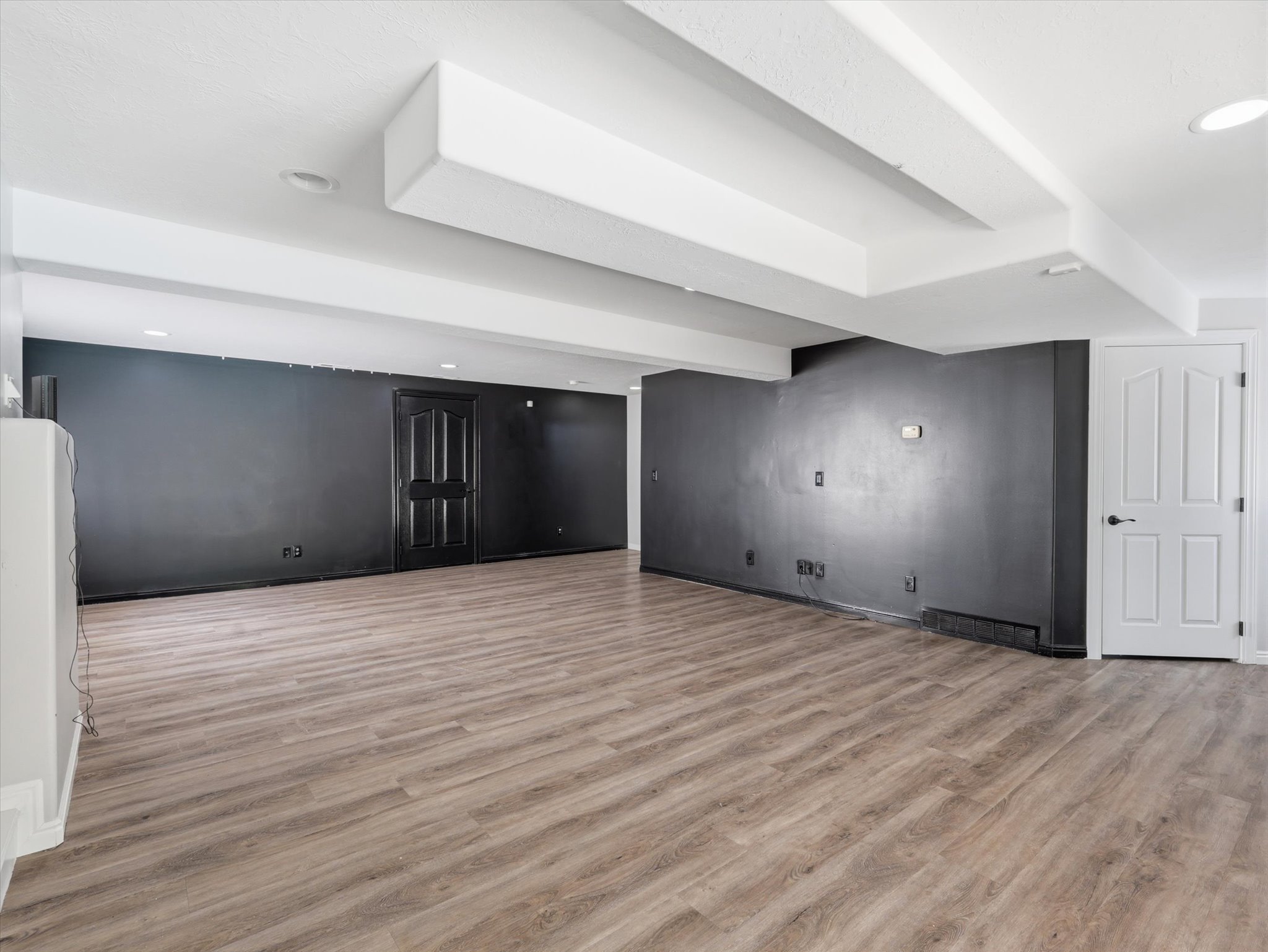 Spacious room featuring wood-finish flooring, recessed ceiling lighting, and a neutral color palette