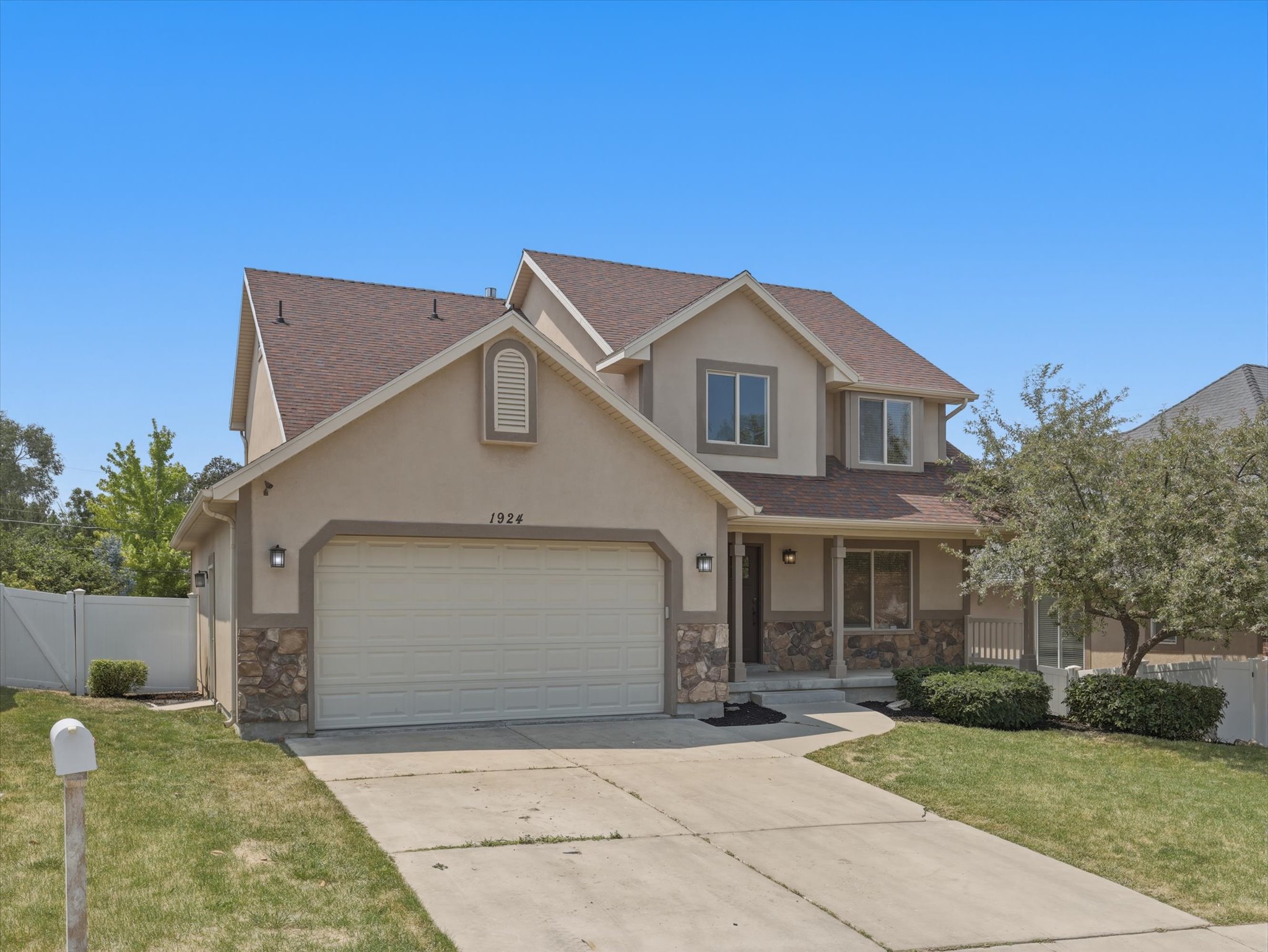 Two-story residence featuring a two-car garage, stone accents, and a covered porch