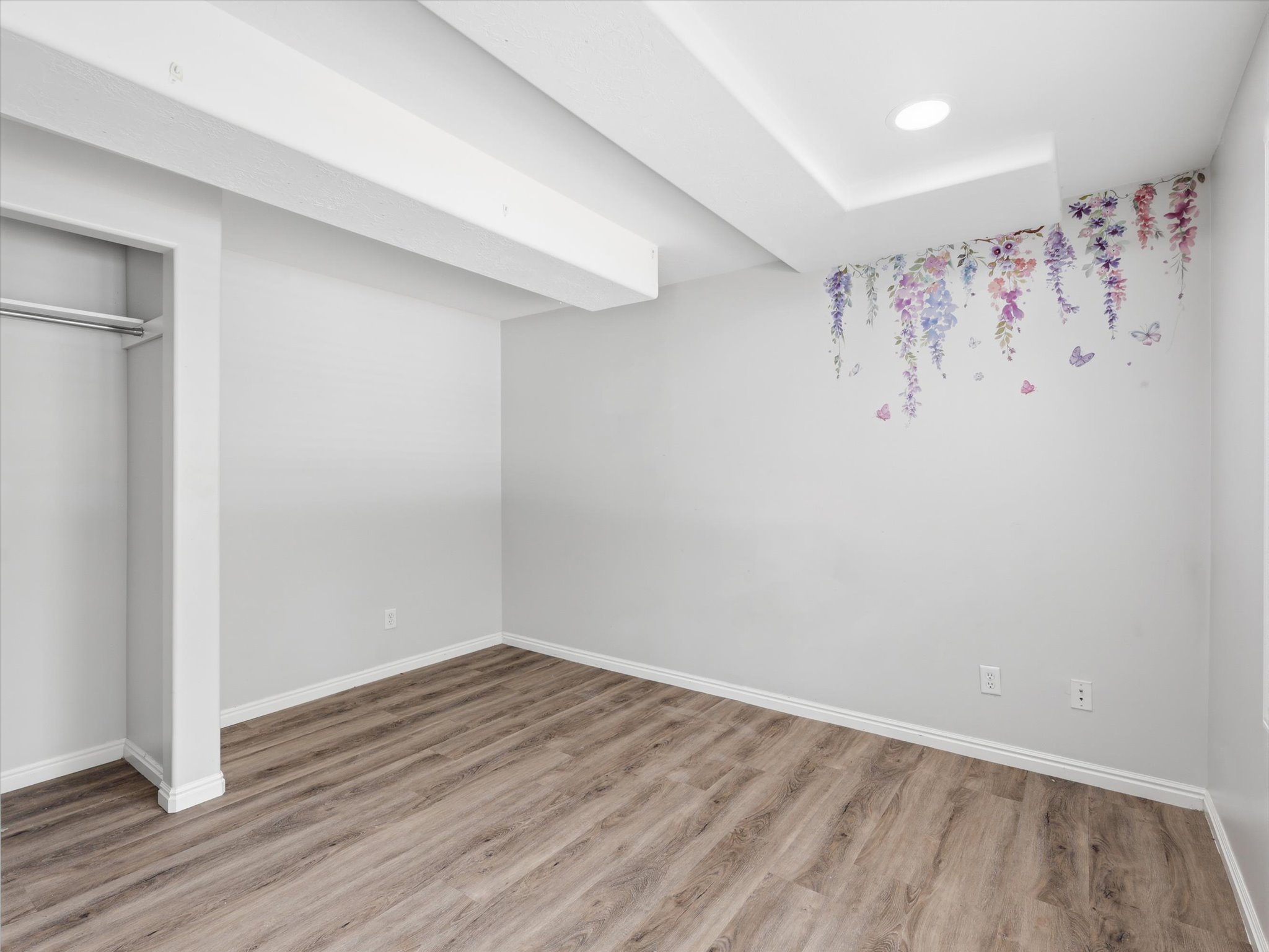 Spacious room featuring wood-finish flooring, white baseboards, and a recessed ceiling light
