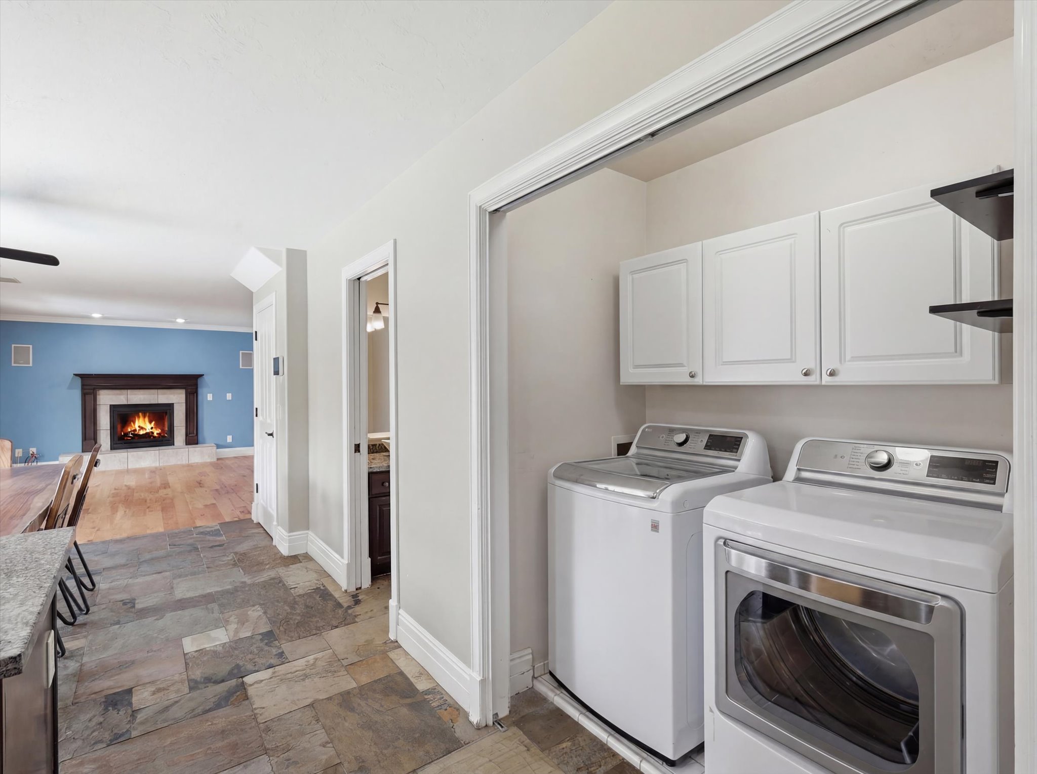 Dedicated laundry area featuring upper white cabinetry and dark floating shelves
