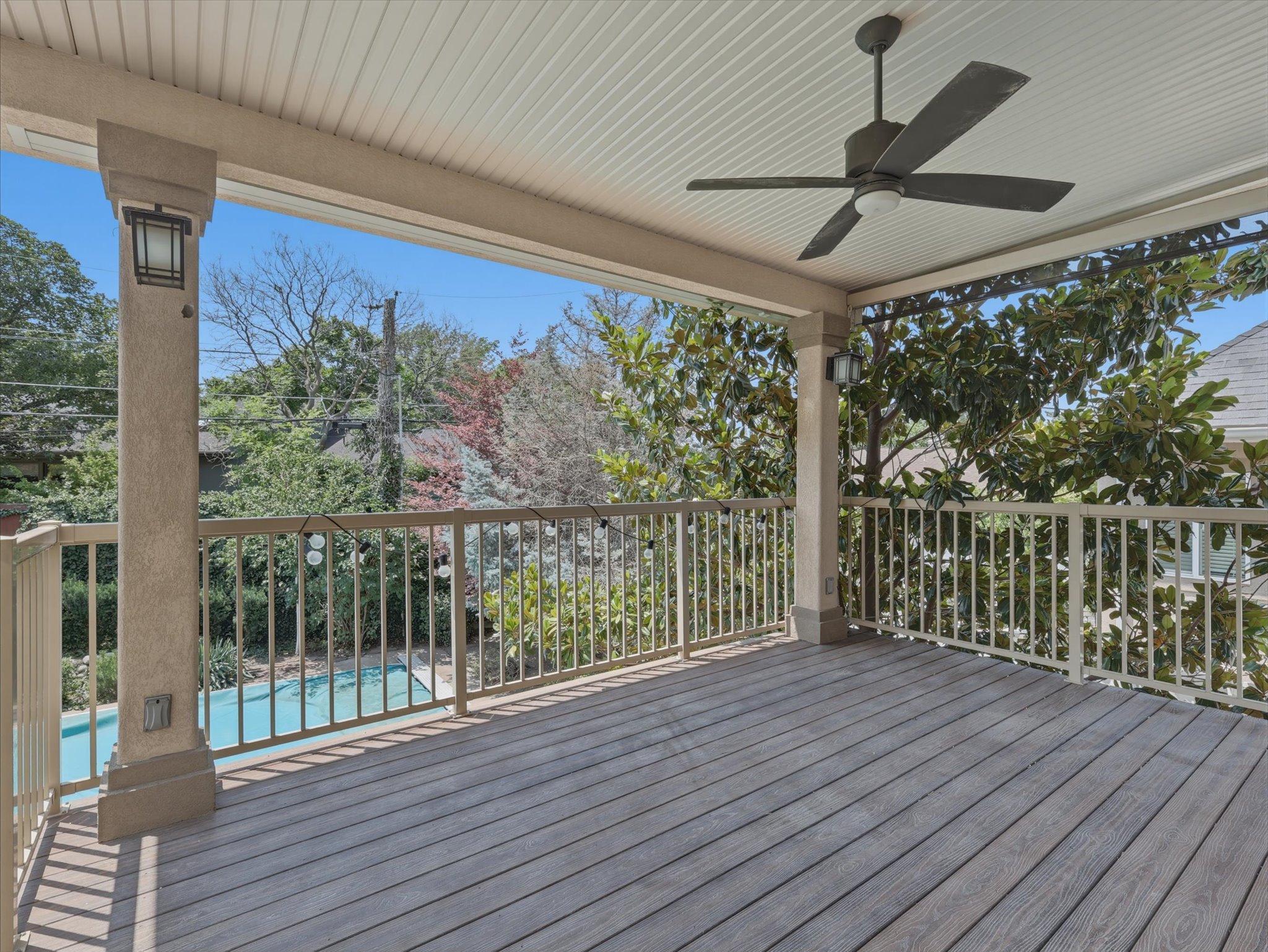 Expansive covered deck featuring wood-finish flooring, a ceiling fan, recessed lighting, and a metal railing system