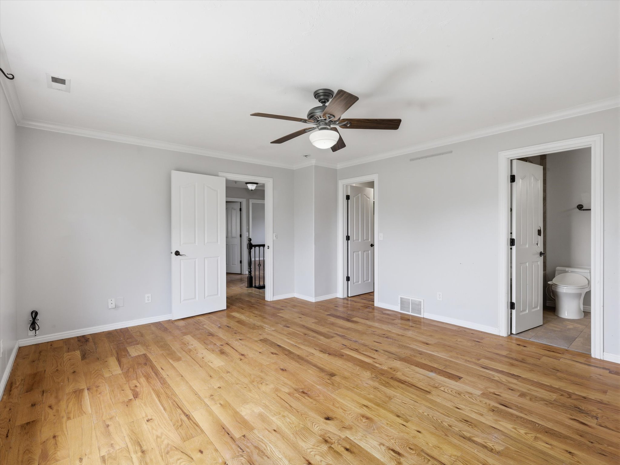 Spacious room featuring wood-finish flooring, light gray walls, and white trim