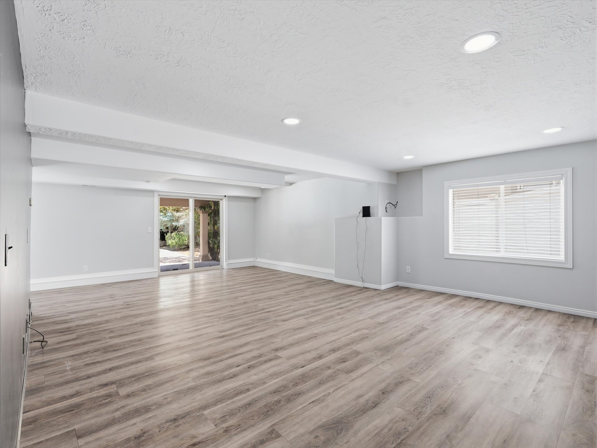 Spacious interior room featuring wood-finish flooring, recessed lighting, and light gray wall paint
