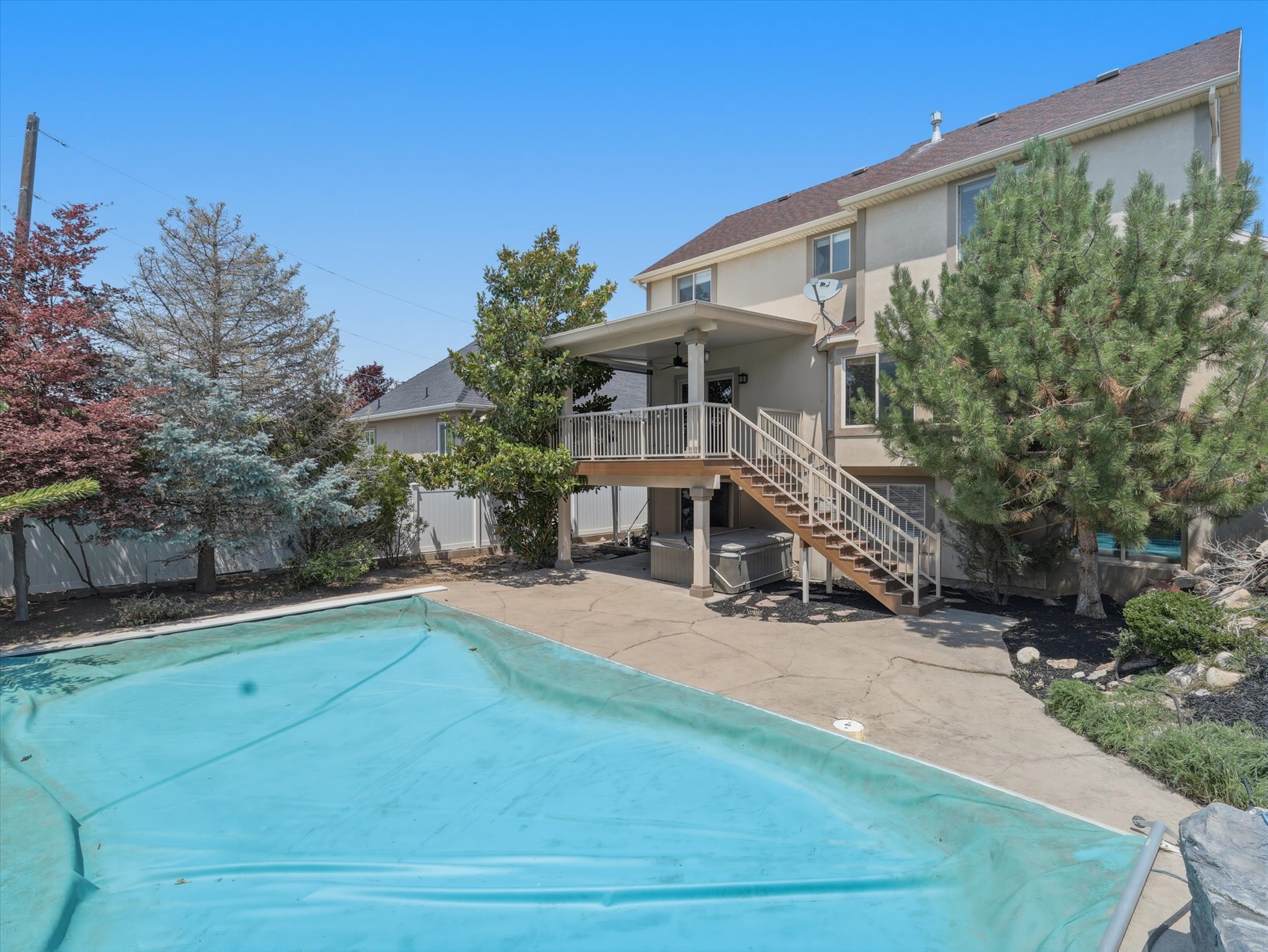 Outdoor living space featuring a covered upper-level deck, a lower-level patio, an outdoor staircase, and a covered swimming pool