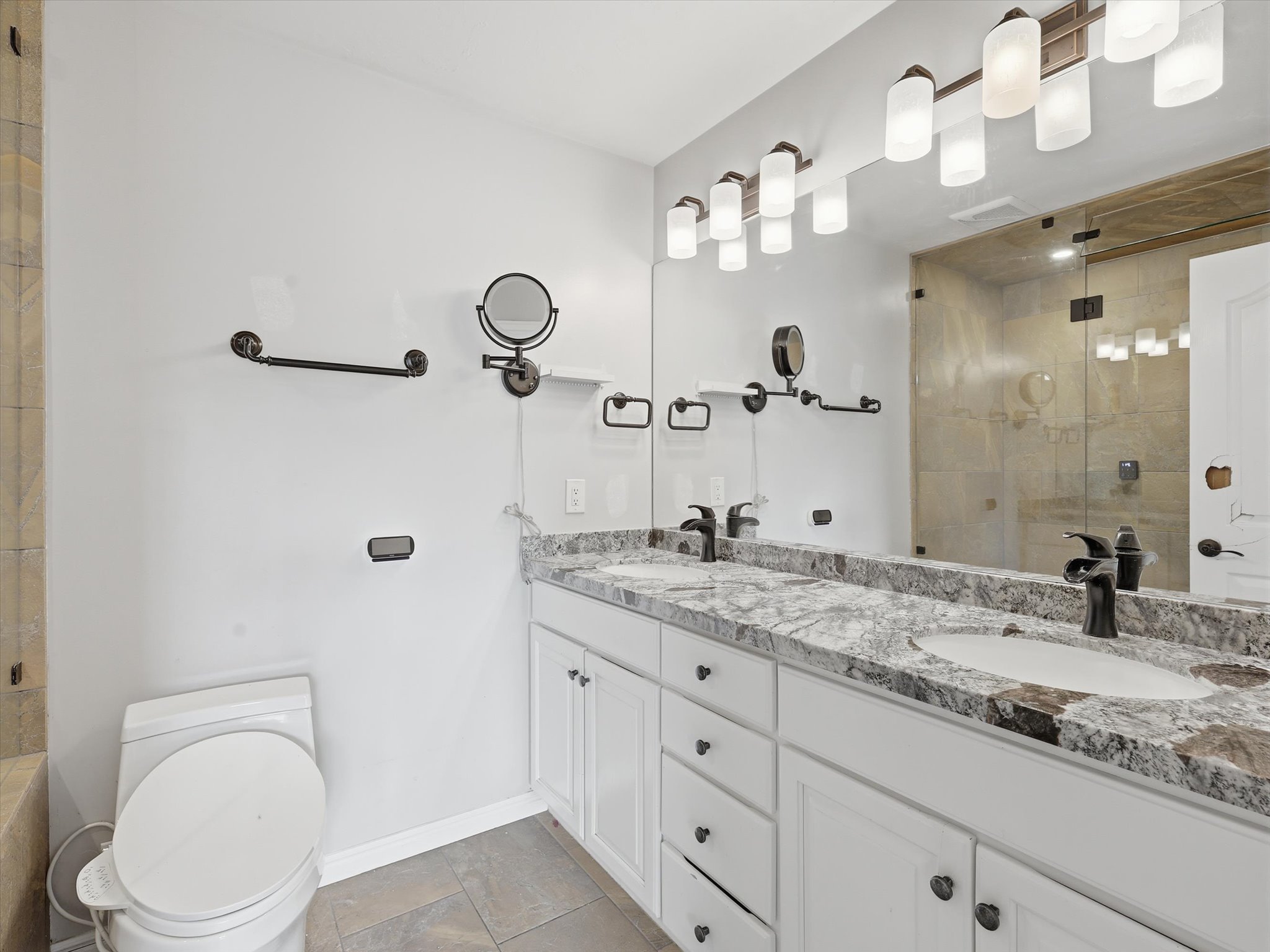 Dual vanity featuring white cabinetry, stone-finish countertops, and matte black fixtures
