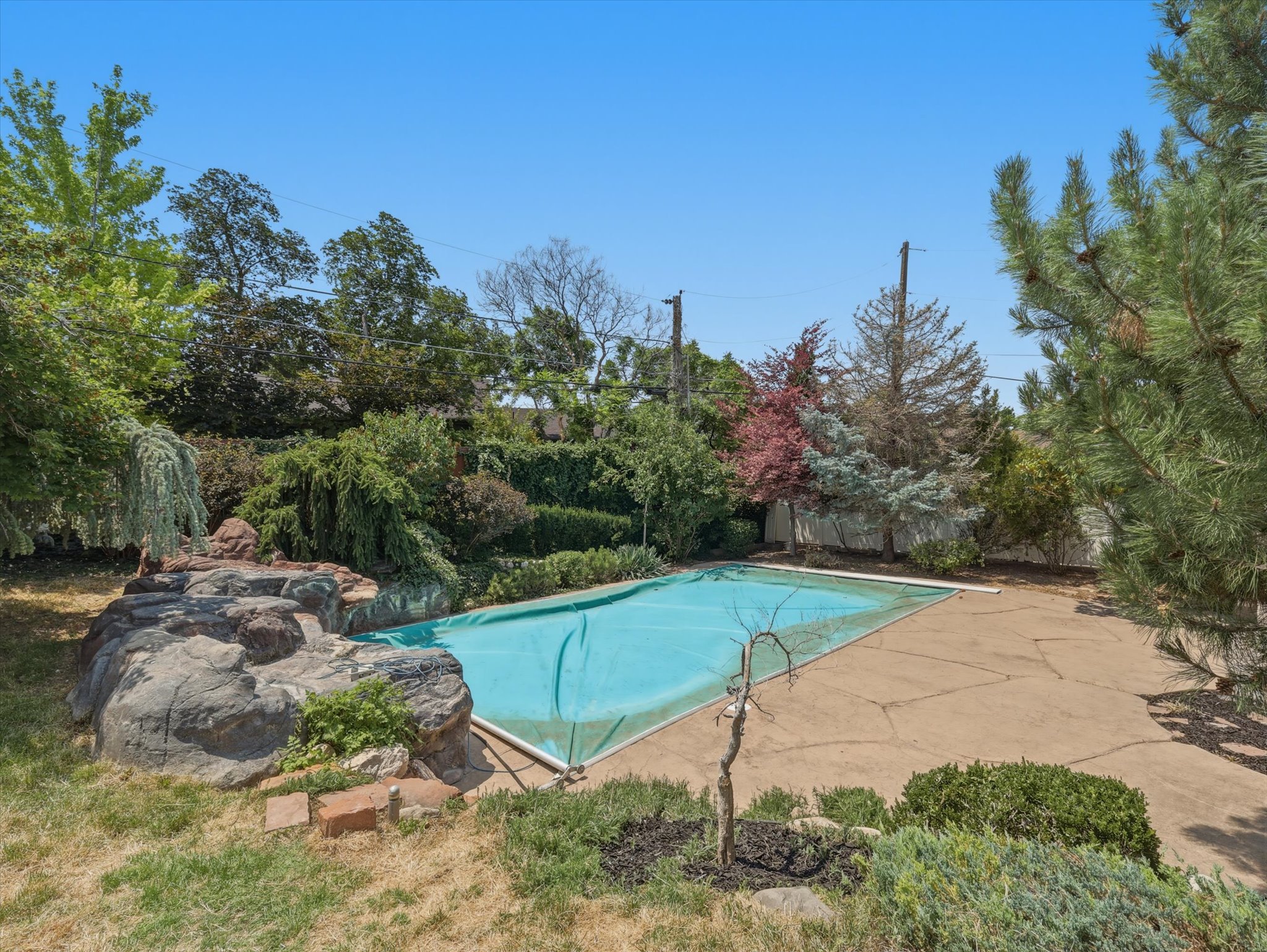 Outdoor swimming pool with a protective cover, surrounded by flagstone-style paving