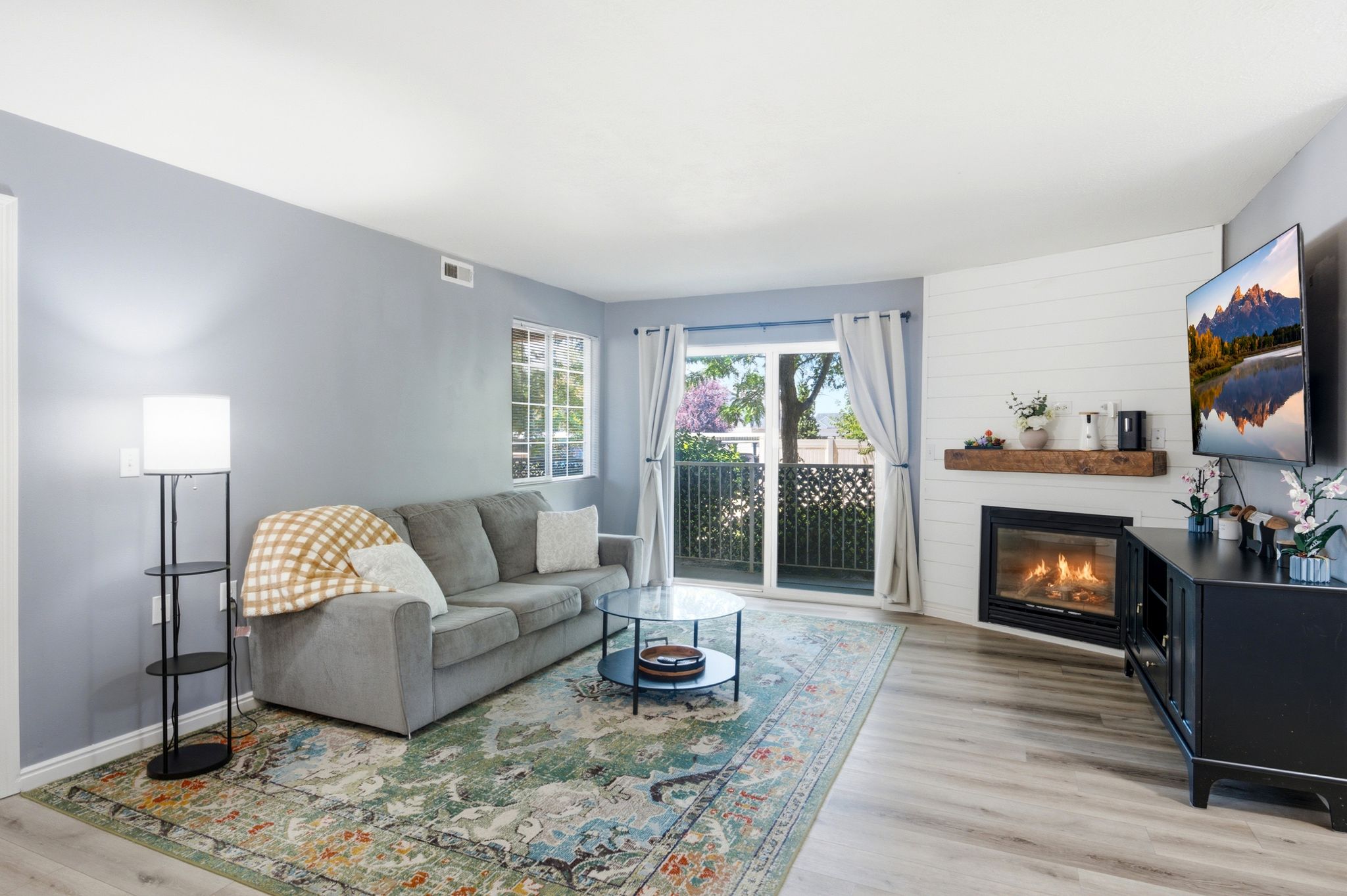 Living area featuring wood-finish flooring, a shiplap accent wall, and a built-in gas fireplace with a wood mantle