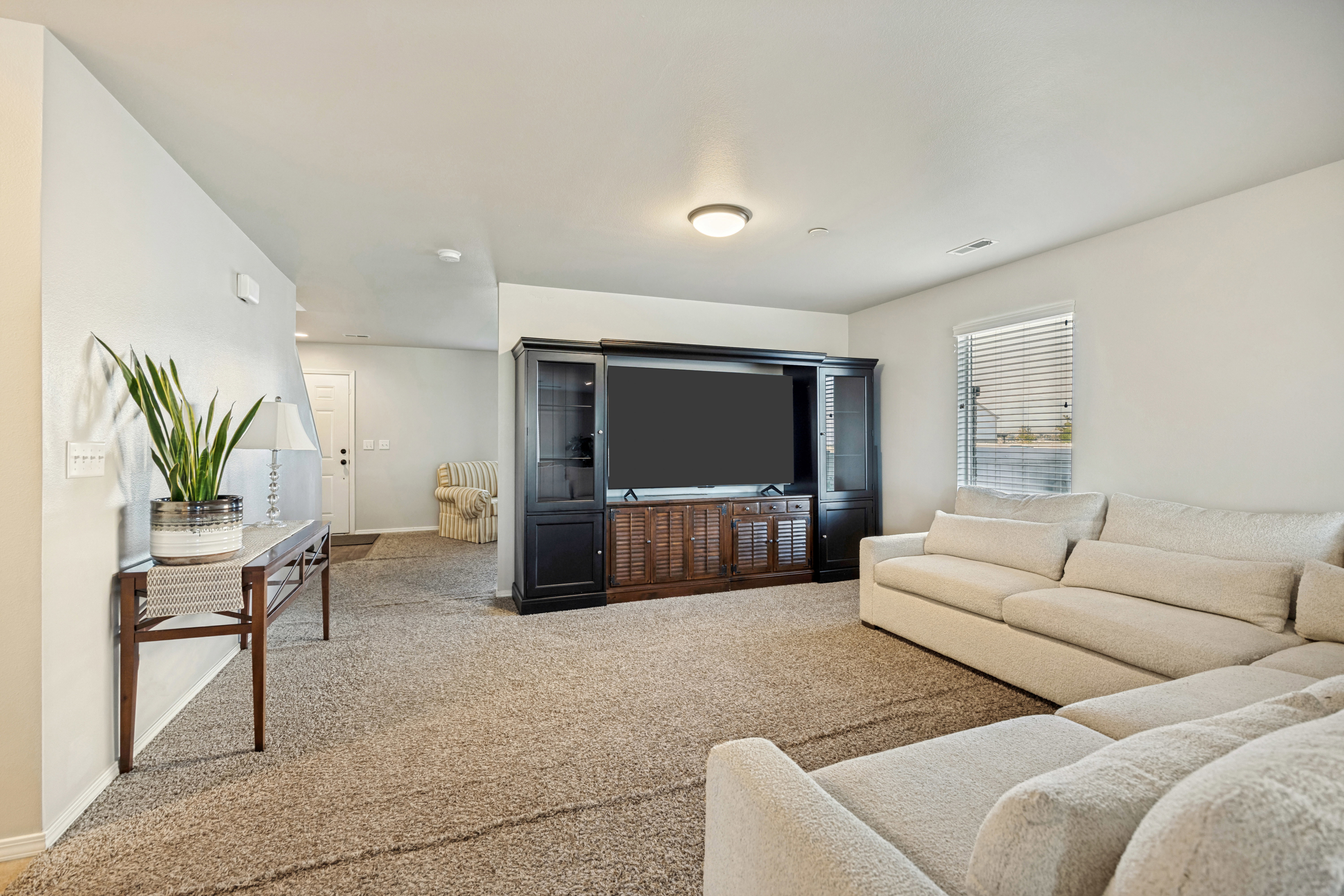 Carpeted living area featuring a single window with blinds and recessed lighting